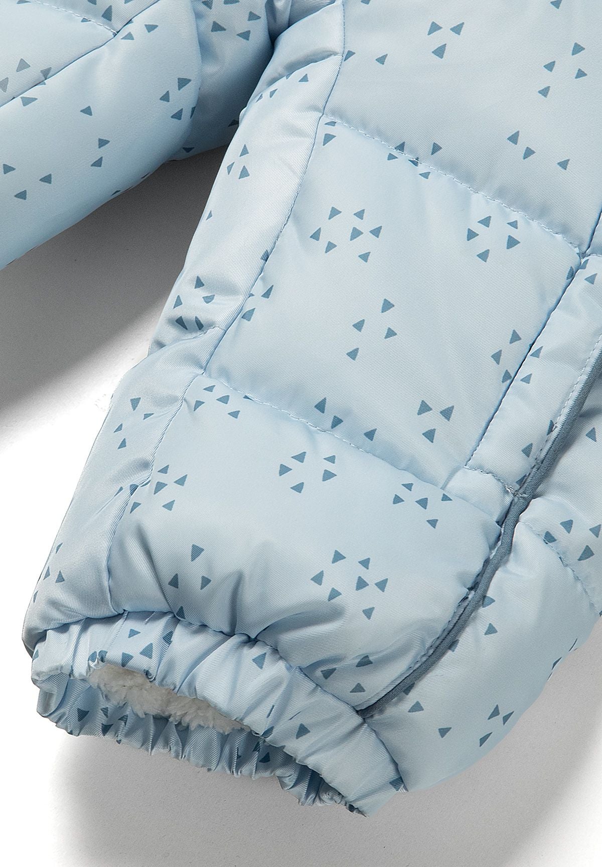 Close-up of pale blue snowsuit fabric printed with scattered dark blue triangles.