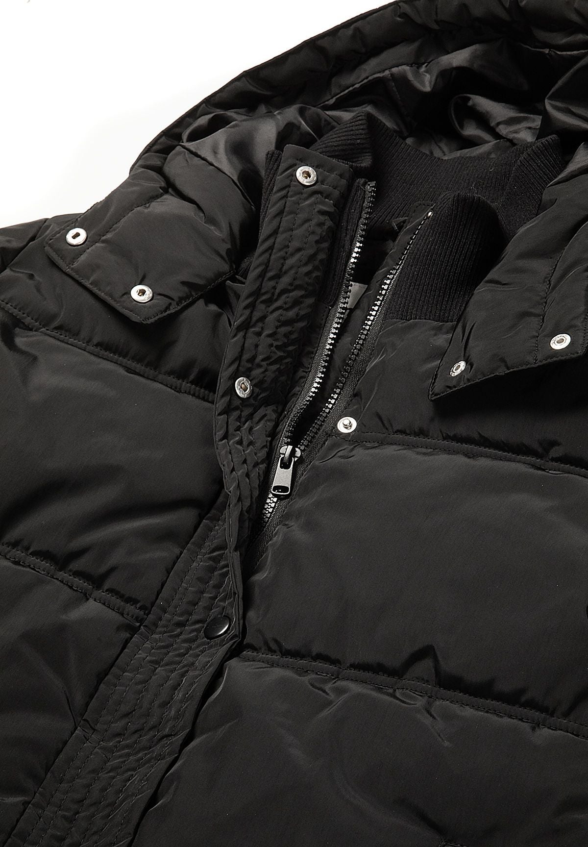 Schwarze Daunenjacke mit Kapuze für Mädchen, Nahaufnahme des Reißverschlusses und der Druckknöpfe.