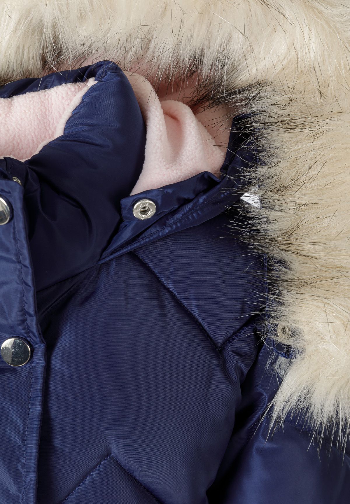 Close-up of cream fluffy hood edging, pale pink lining and silver snaps on the navy coat.
