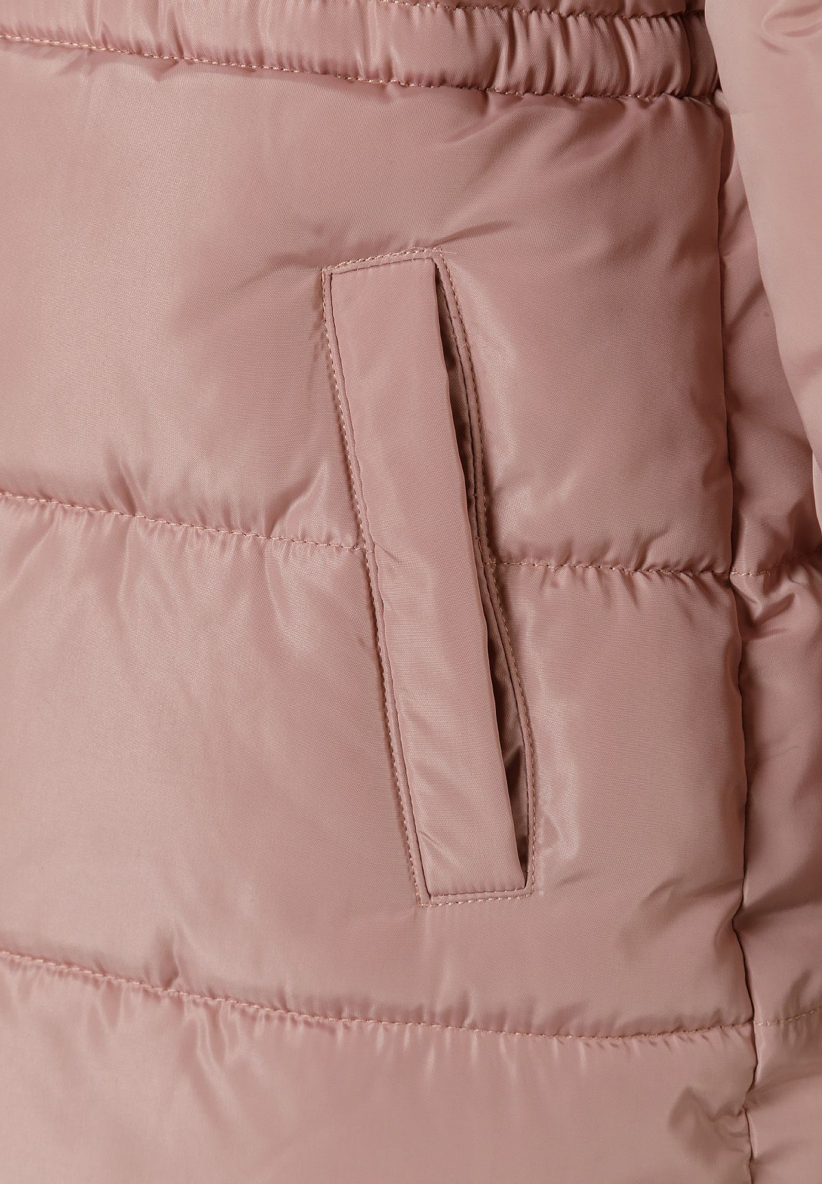 Close-up of a vertical welt pocket in the dusty pink quilted coat below its gathered waist.