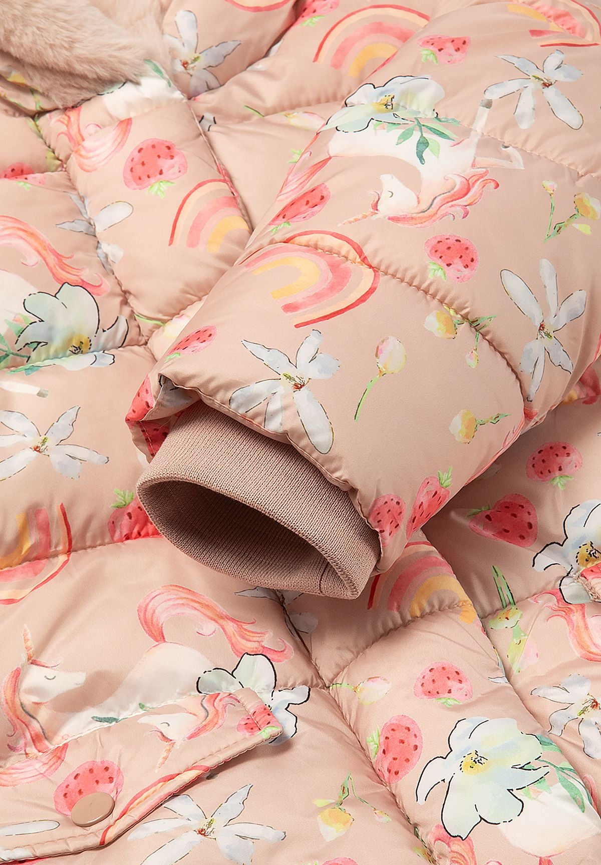 Close-up of a beige-pink rib-knit inner cuff beneath the unicorn-print padded sleeve.