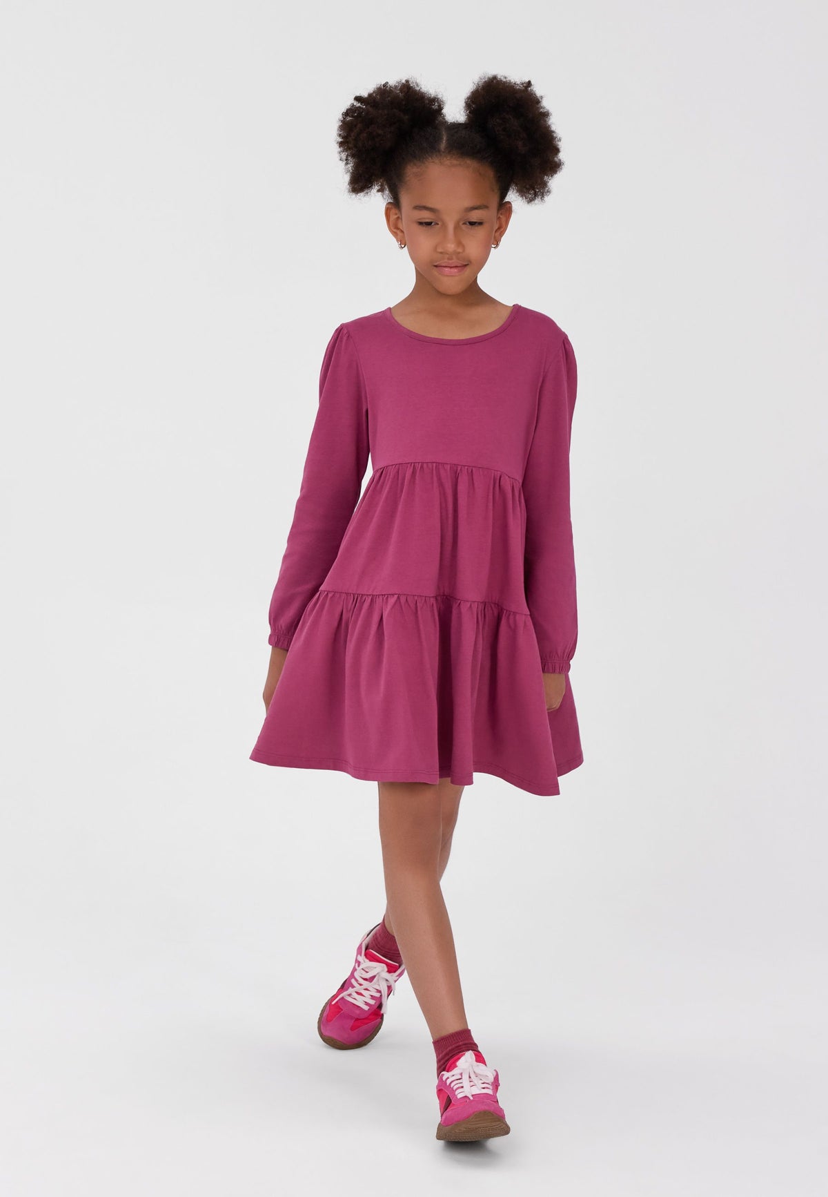 Girl wearing a berry-pink long-sleeved dress with a gathered two-tier skirt.