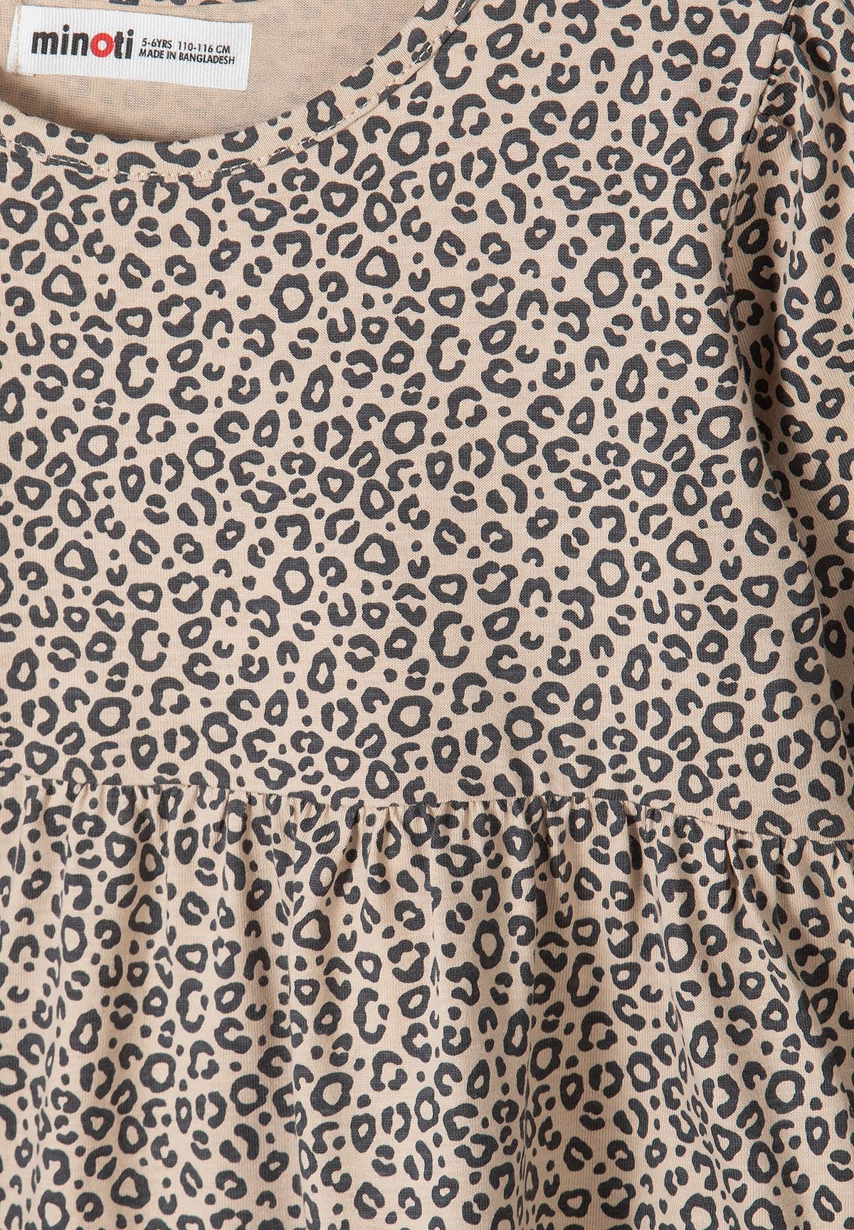 Close-up of dark leopard rosettes on sand fabric of tiered dress.