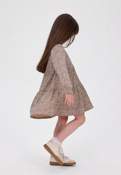Girl in a sand-coloured leopard-print tiered dress with long puffed sleeves.