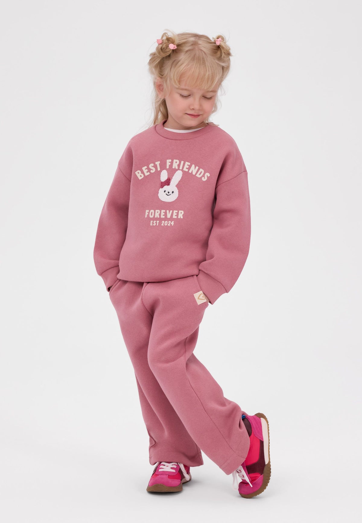 Set composto da felpa rosa con coniglietto e pantaloni a gamba larga da bambina, modella vista di fronte.