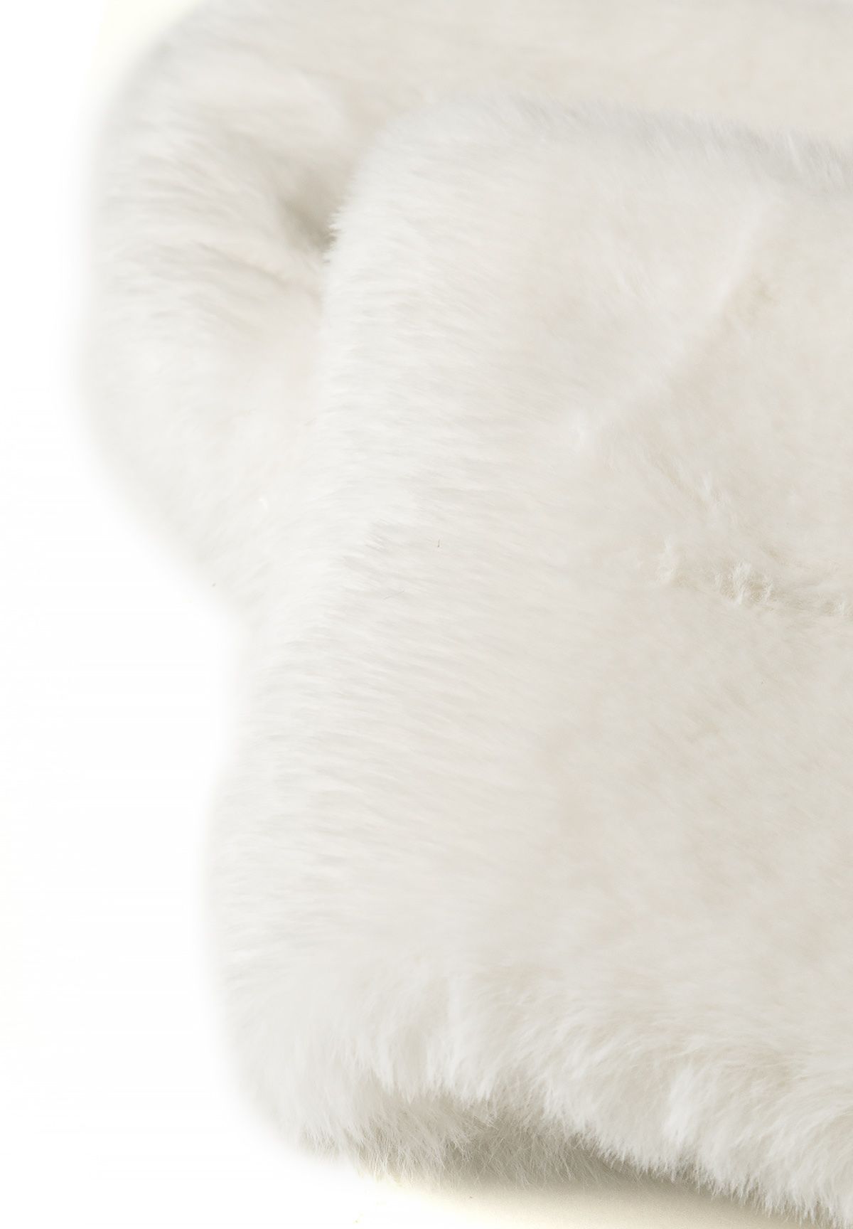 Close-up of the folded cream scarf's smooth plush faux-fur surface and rounded edge.