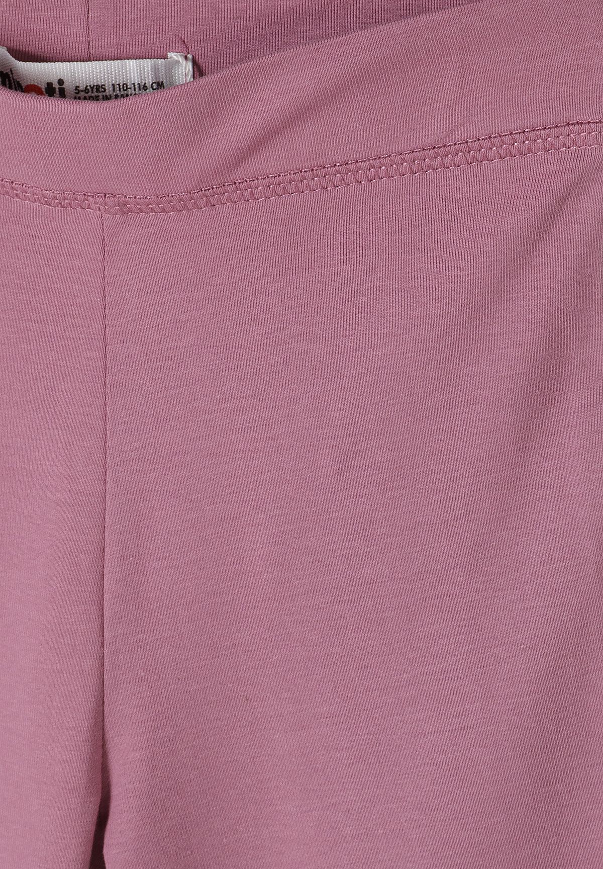 Close-up of dusty pink leggings' fine vertical ribs and stitched waistband.