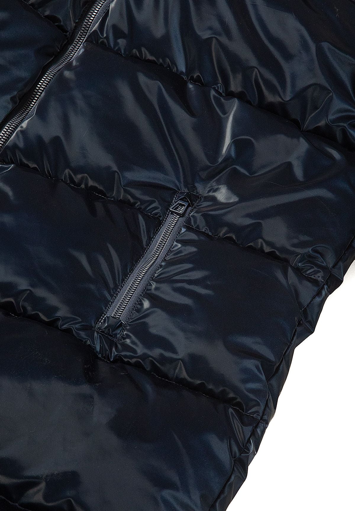 Close-up of a vertical zipped side pocket set into glossy navy quilted panels of the long coat.