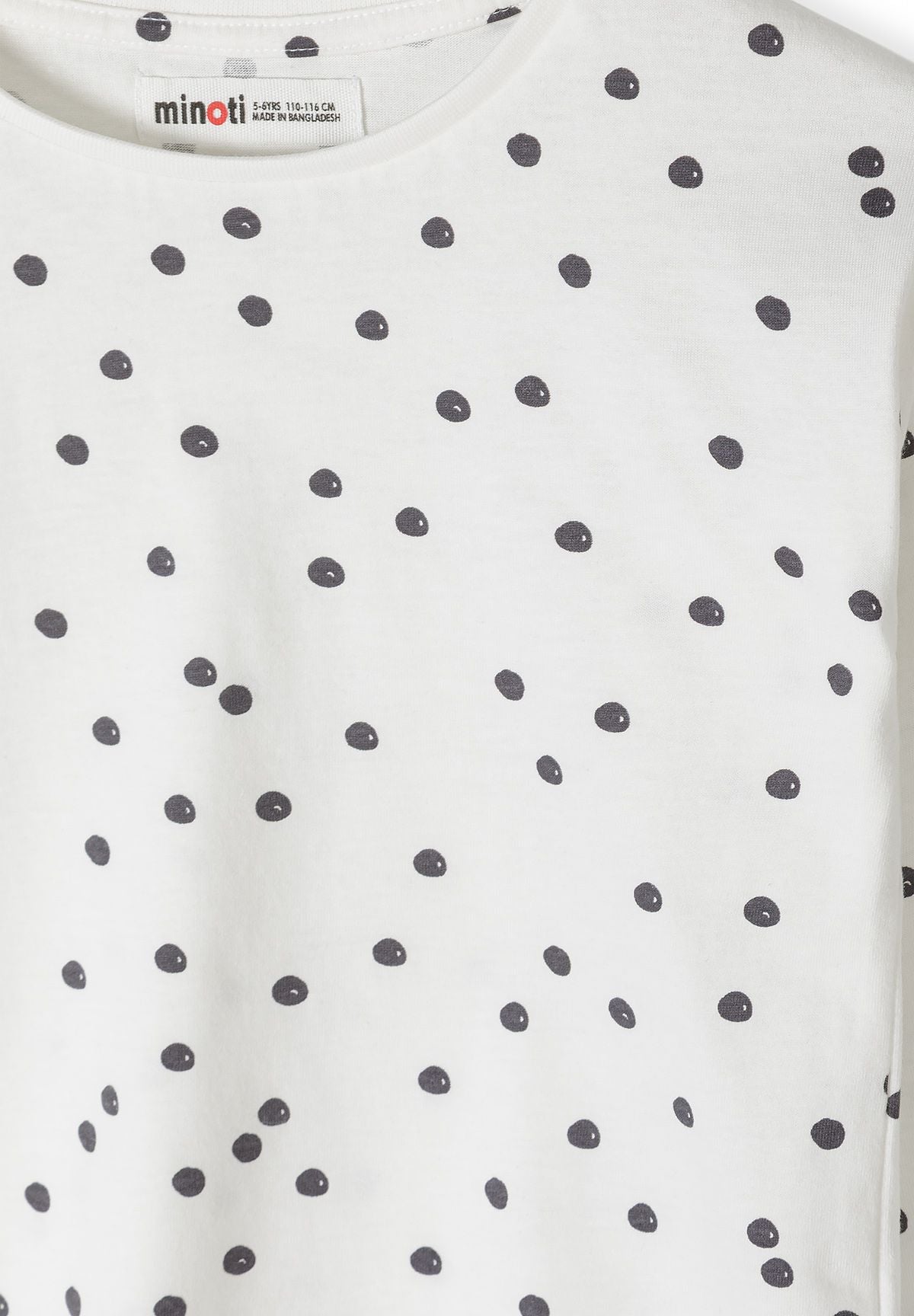 Close-up of irregular charcoal spots on white long-sleeve top.