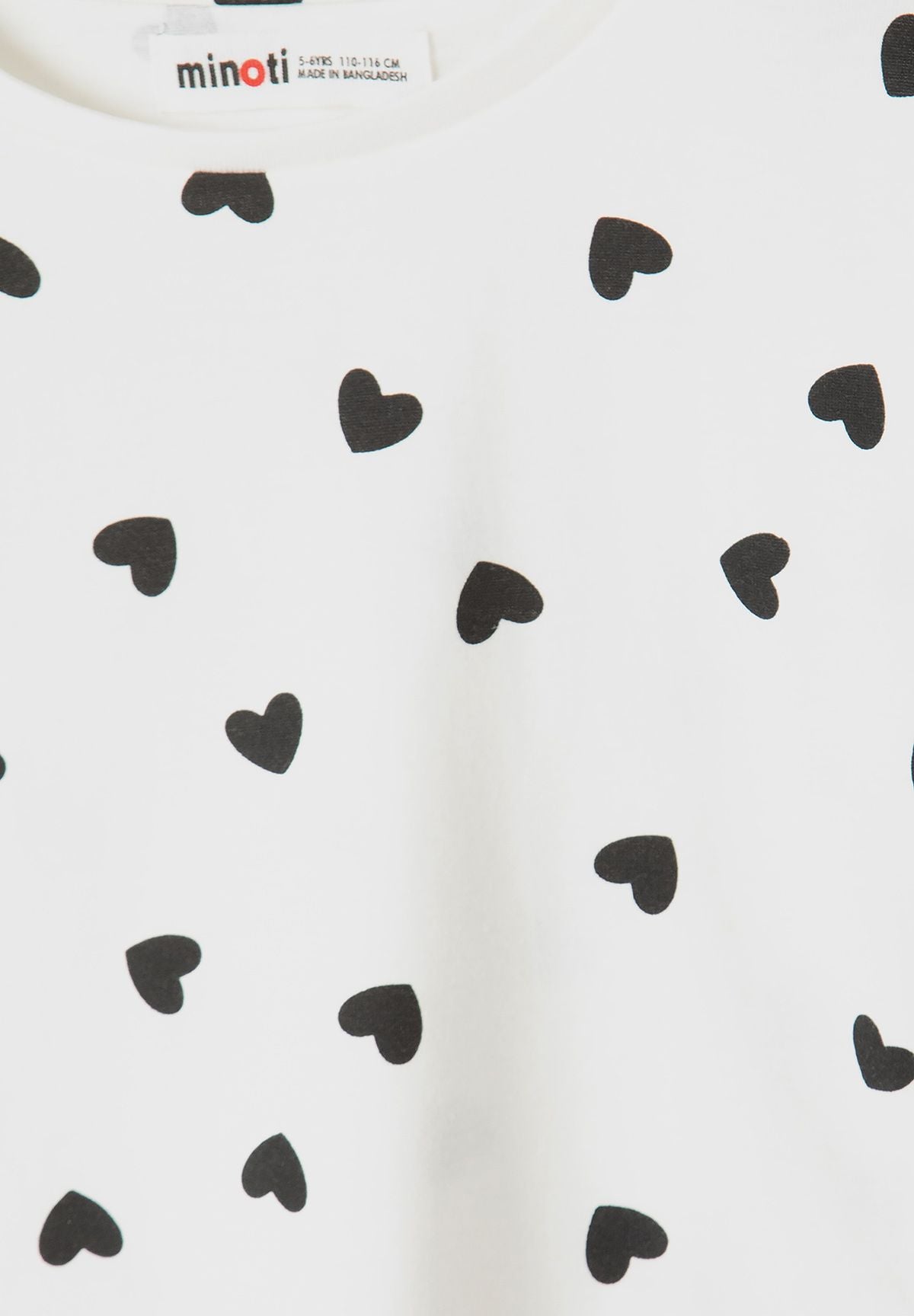 Close-up of black hearts scattered on white top.