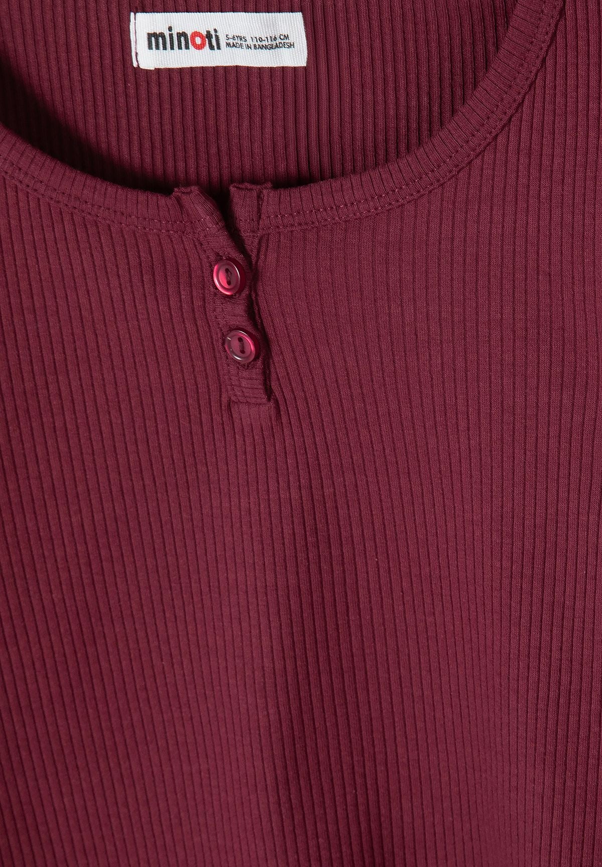 Close-up of burgundy ribbed top's rounded neck and two buttons.