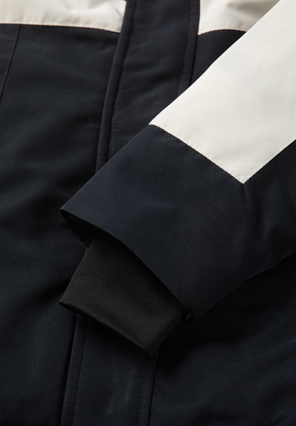 Layered parka cuff showing a black ribbed inner sleeve below a black outer cuff and cream panel.