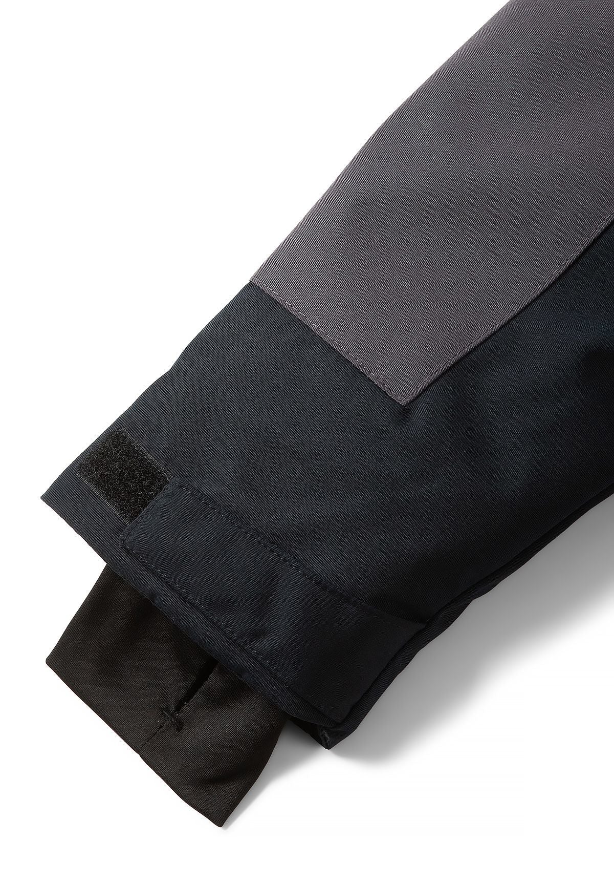 Parka cuff detail with a black hook-and-loop adjustment tab and a ribbed inner sleeve cuff.