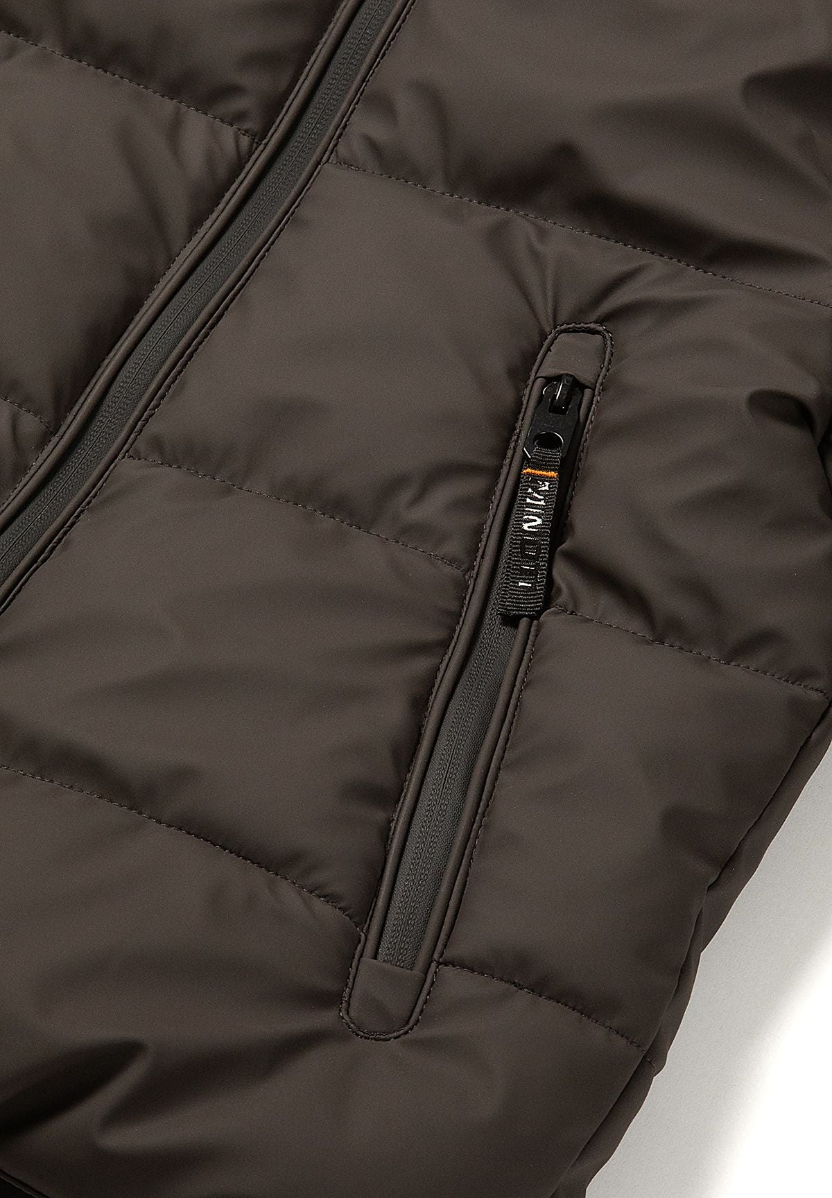 Close-up of an extra-long black front pocket zip with a branded pull on a brown puffer jacket.