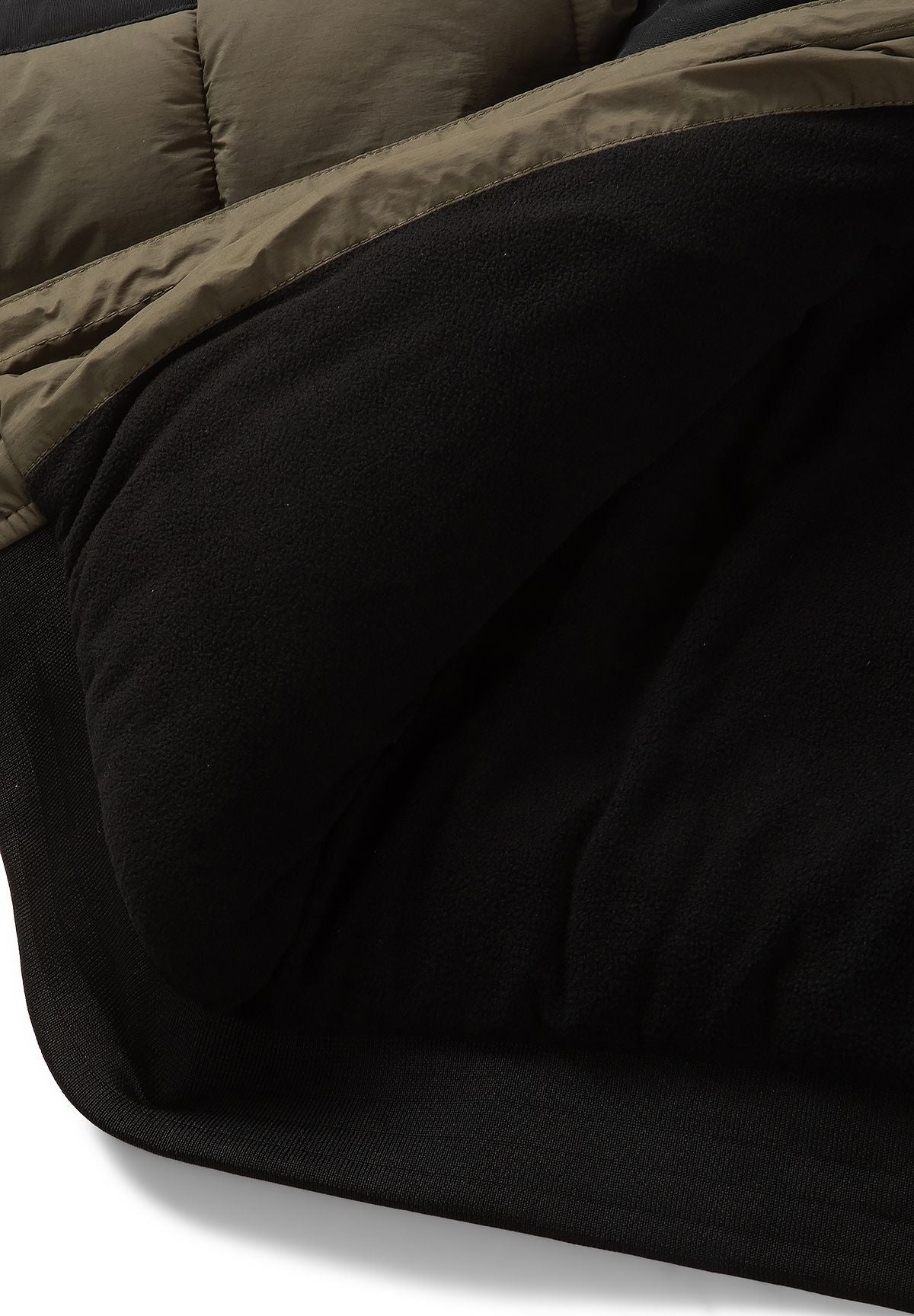 Close-up of the black fabric lining inside the olive quilted hooded jacket.