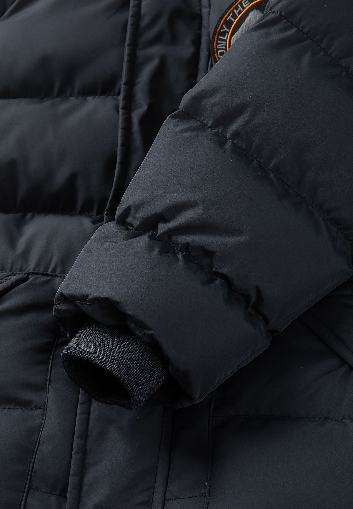 Marineblauwe gewatteerde parka voor jongens met afneembare capuchonrand, detail van de binnenkant van de manchet.