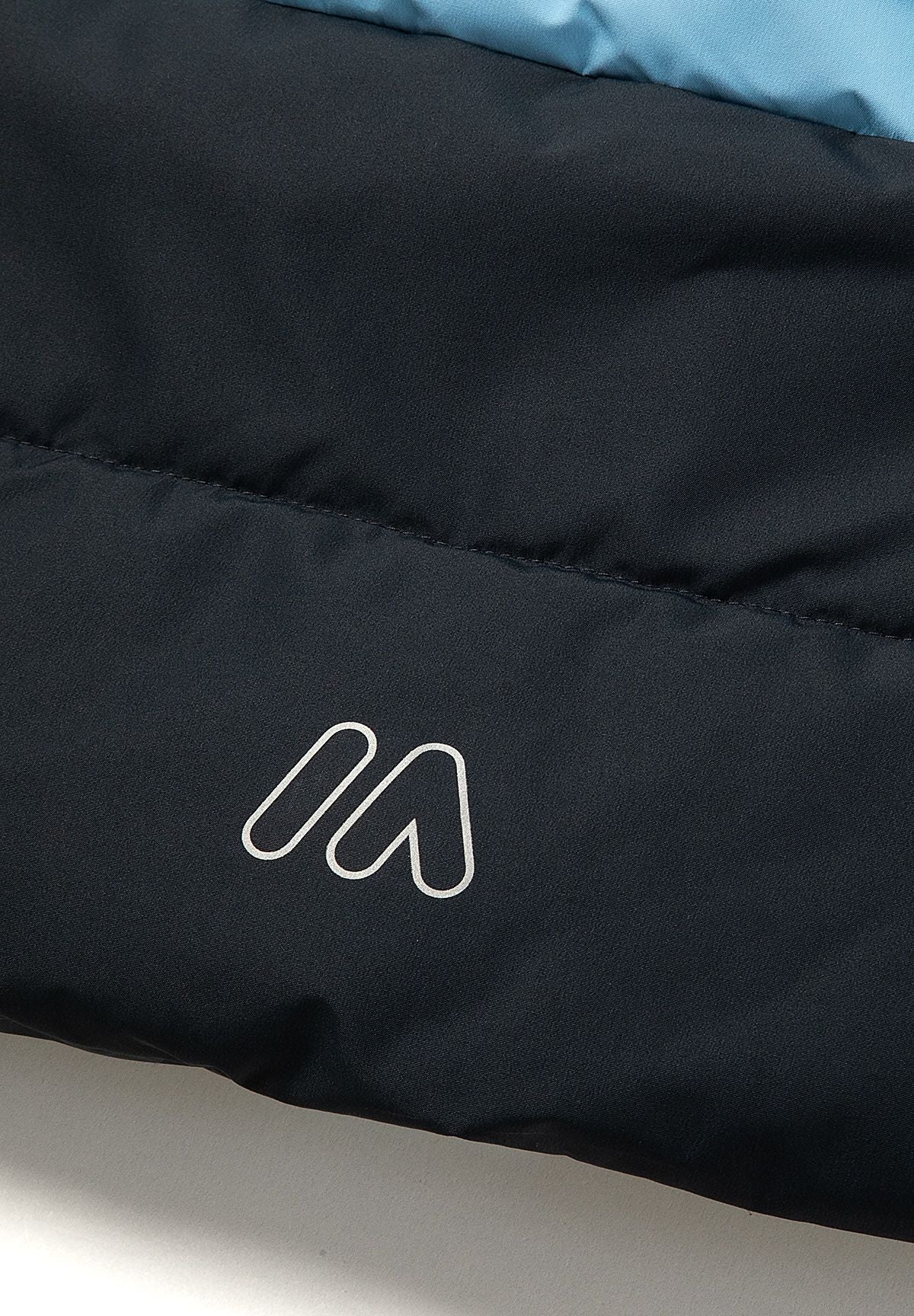 Lichtblauwe en marineblauwe gewatteerde parka met kleurblokken voor jongens, detail van het bedrukte logo op de rug.