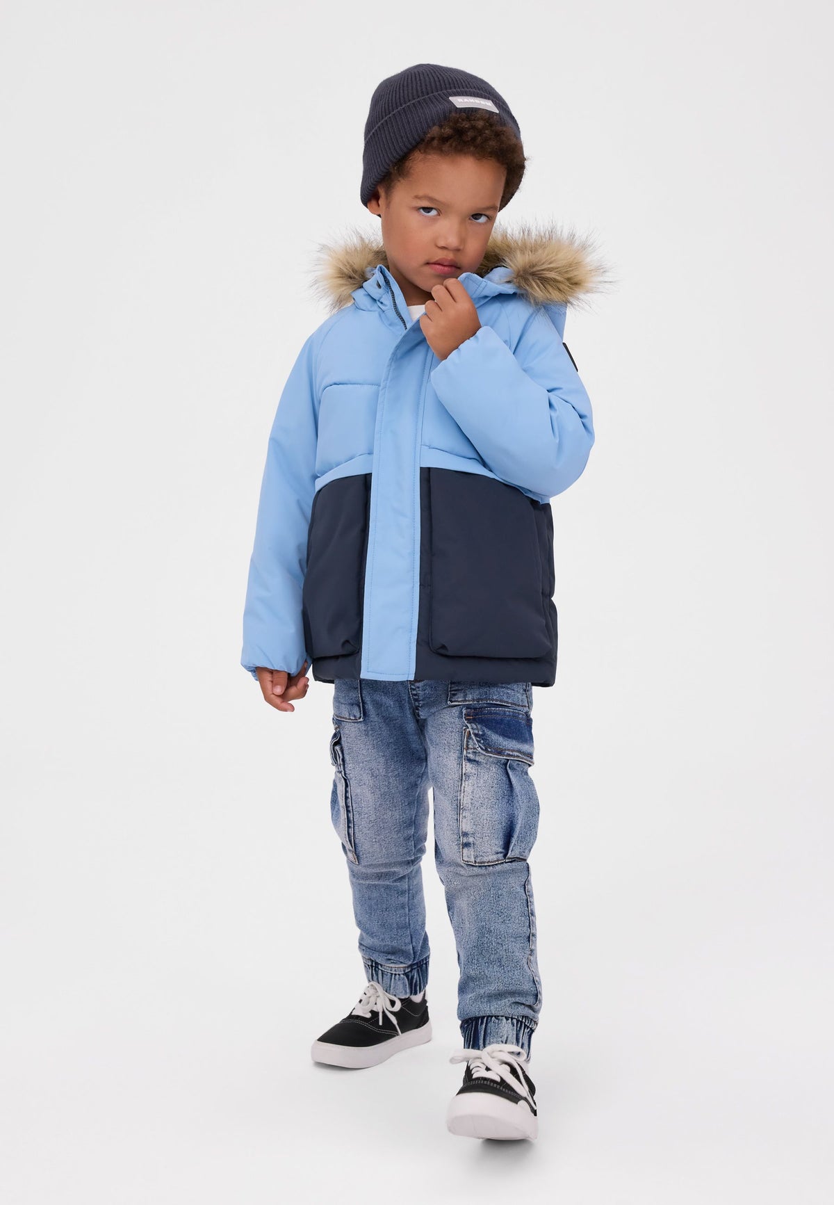 Lichtblauwe en marineblauwe gewatteerde parka met kleurblokken voor jongens, vooraanzicht op model.