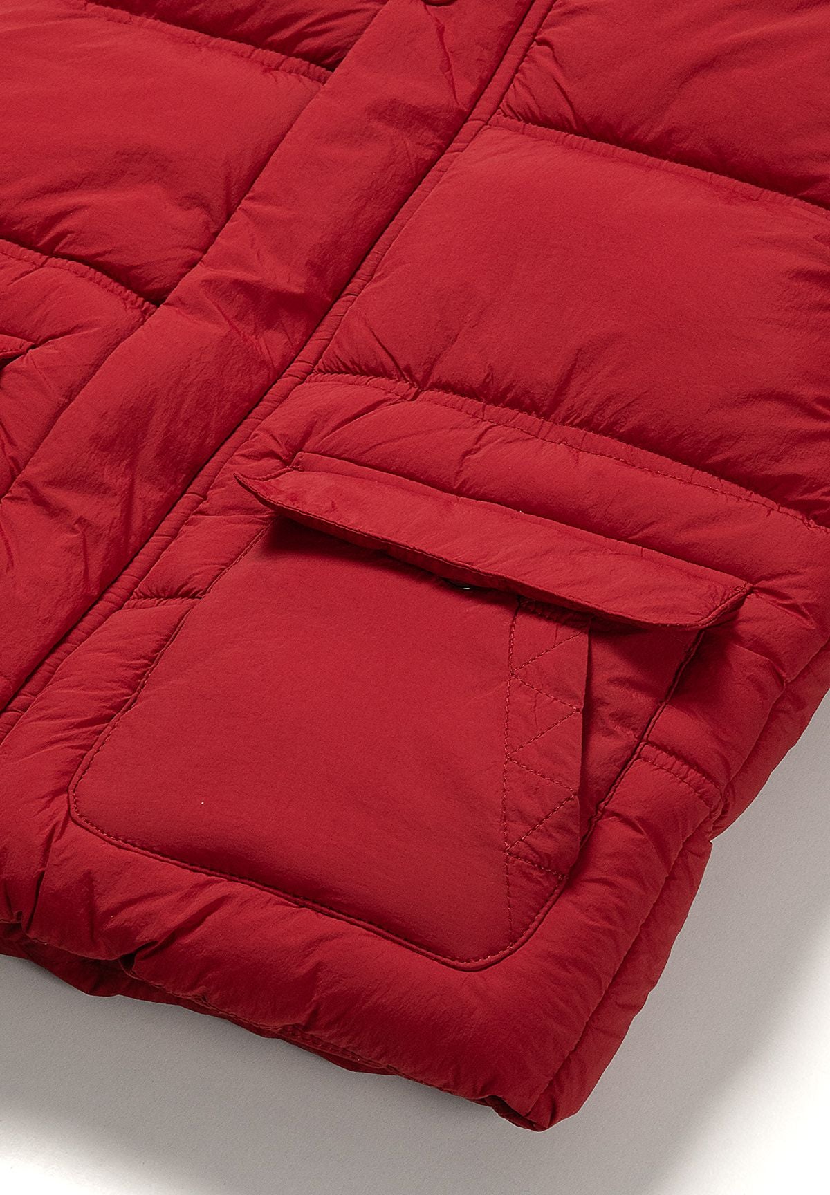Close-up of a large sewn-on red front pocket with a broad padded flap on the puffer coat.