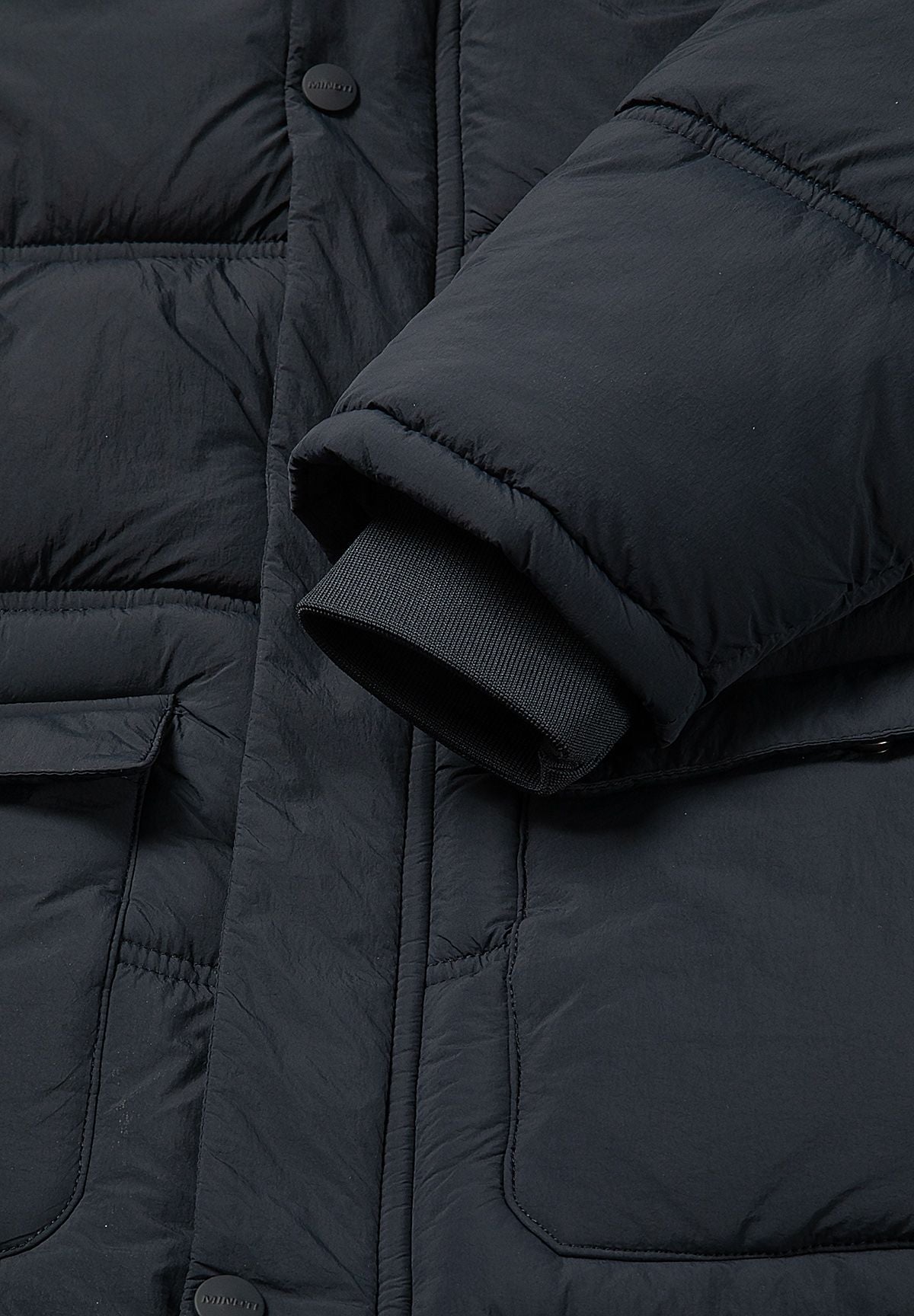 Dark ribbed inner cuff protruding from the wider navy padded coat sleeve.