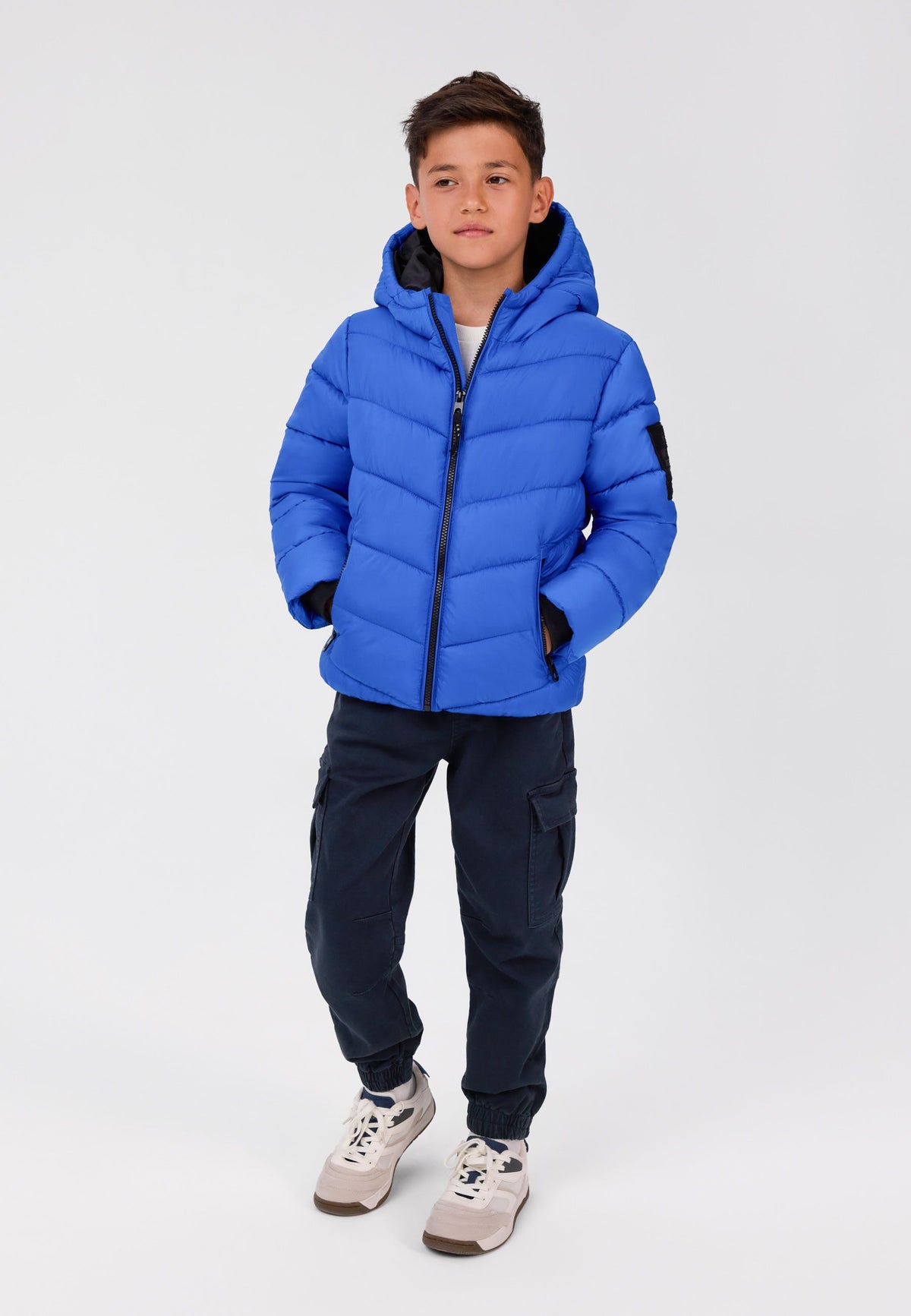 Blauwe pufferjas met capuchon voor jongens, met ritszakken, vooraanzicht op model.