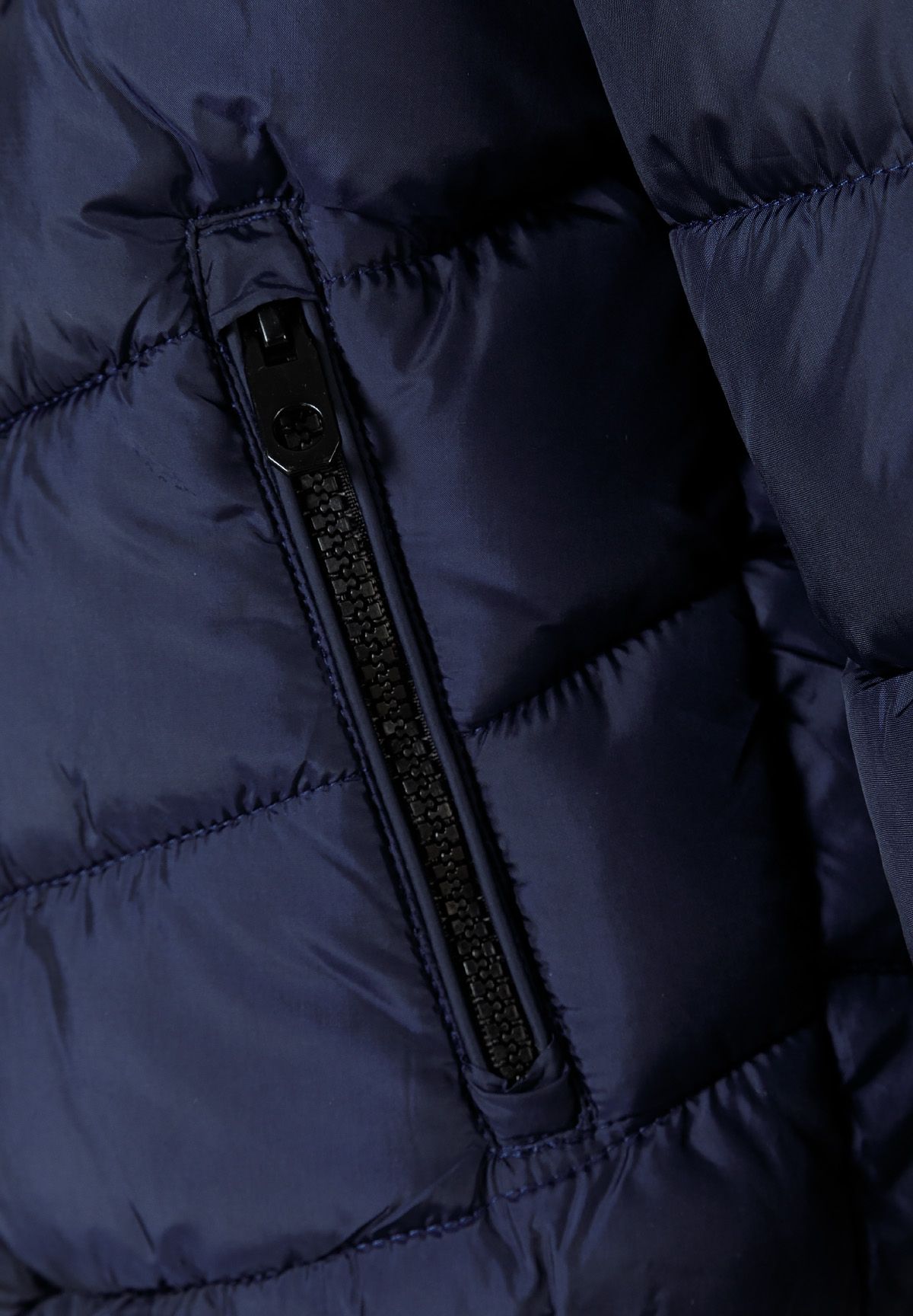 Close-up of a black zip on a slanted side pocket in navy padded fabric.