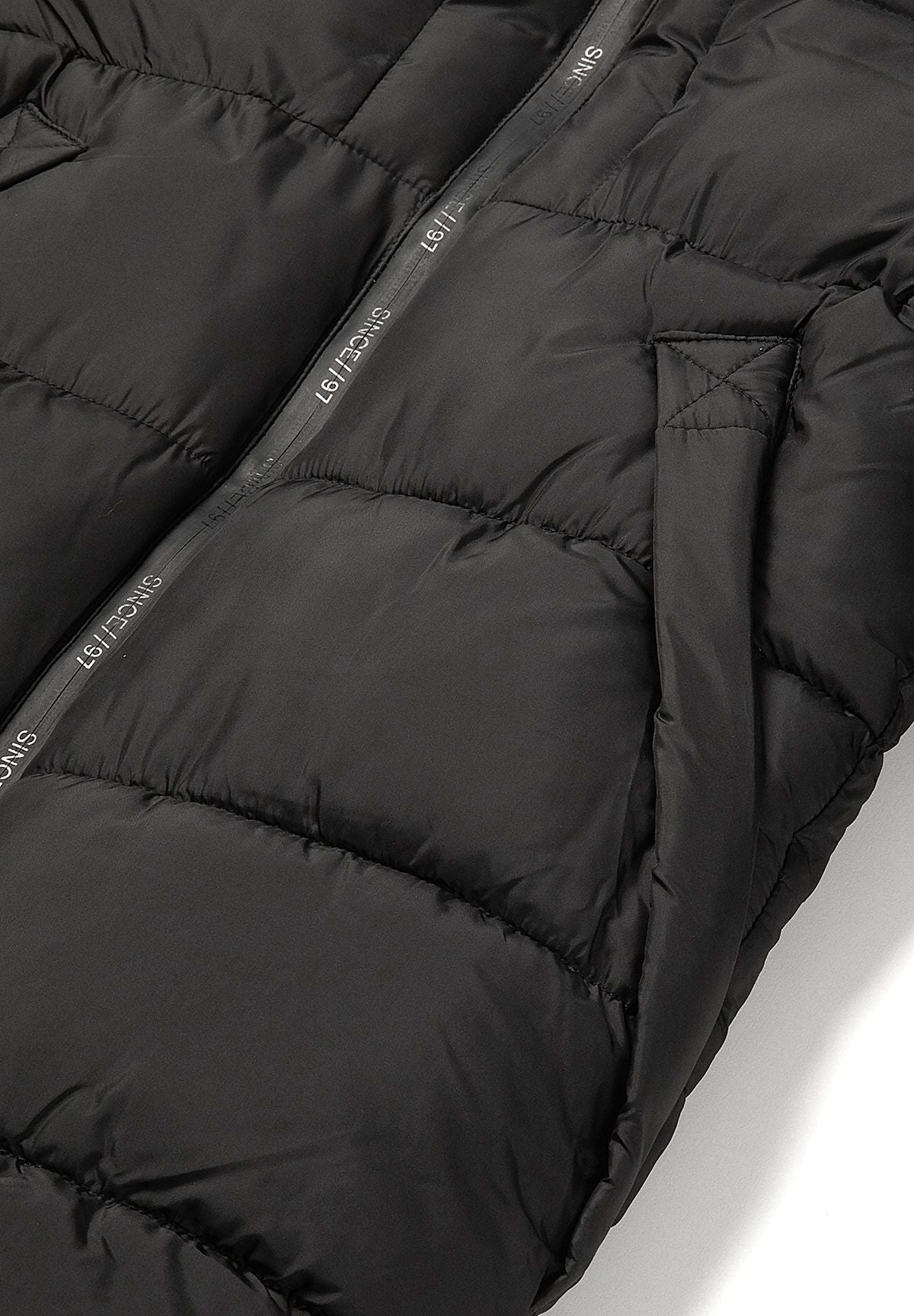 Close-up of a vertical lower pocket opening and printed zip tape on the black padded coat.