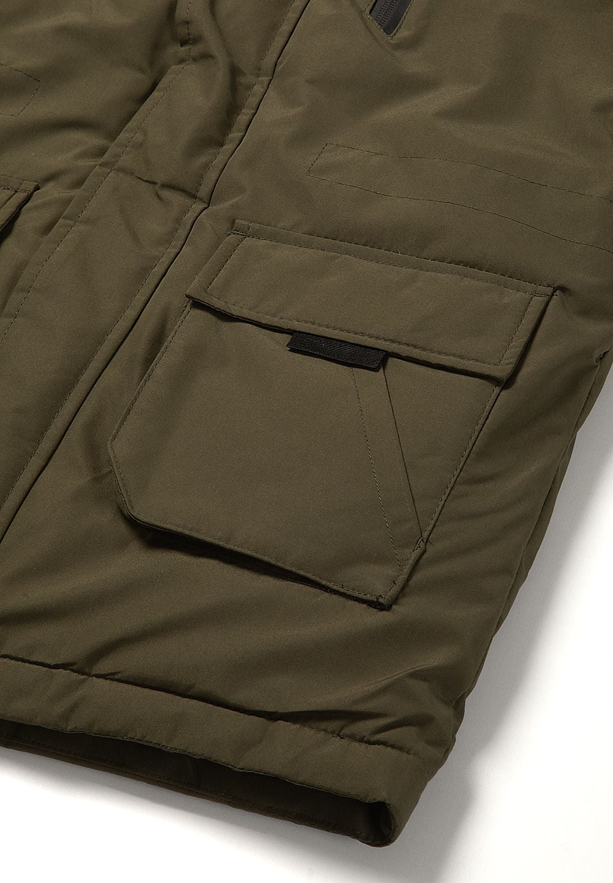 Lower khaki parka pocket with rounded patch shape, straight flap and black pull tab above the long hem.