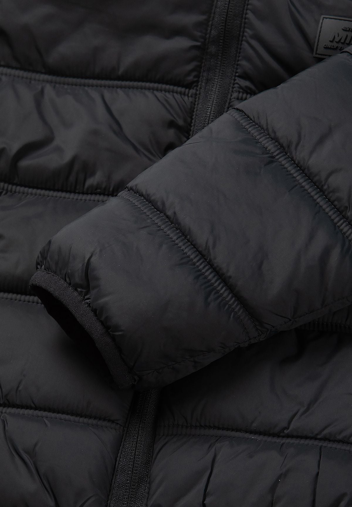 Elastic-edged black sleeve cuff against the jacket's padded horizontal quilting.