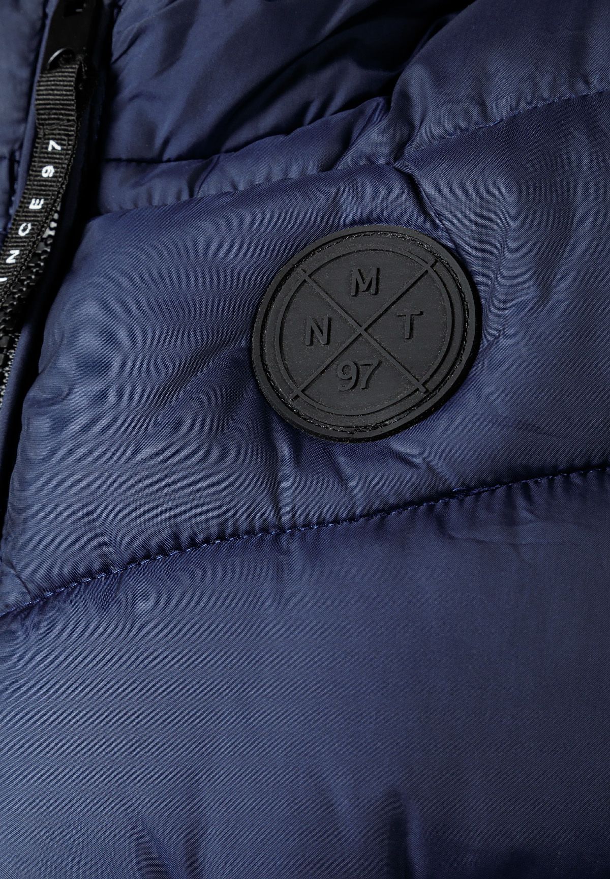 Marineblaue, wattierte Kapuzenweste für Jungen, Nahaufnahme des Emblems.