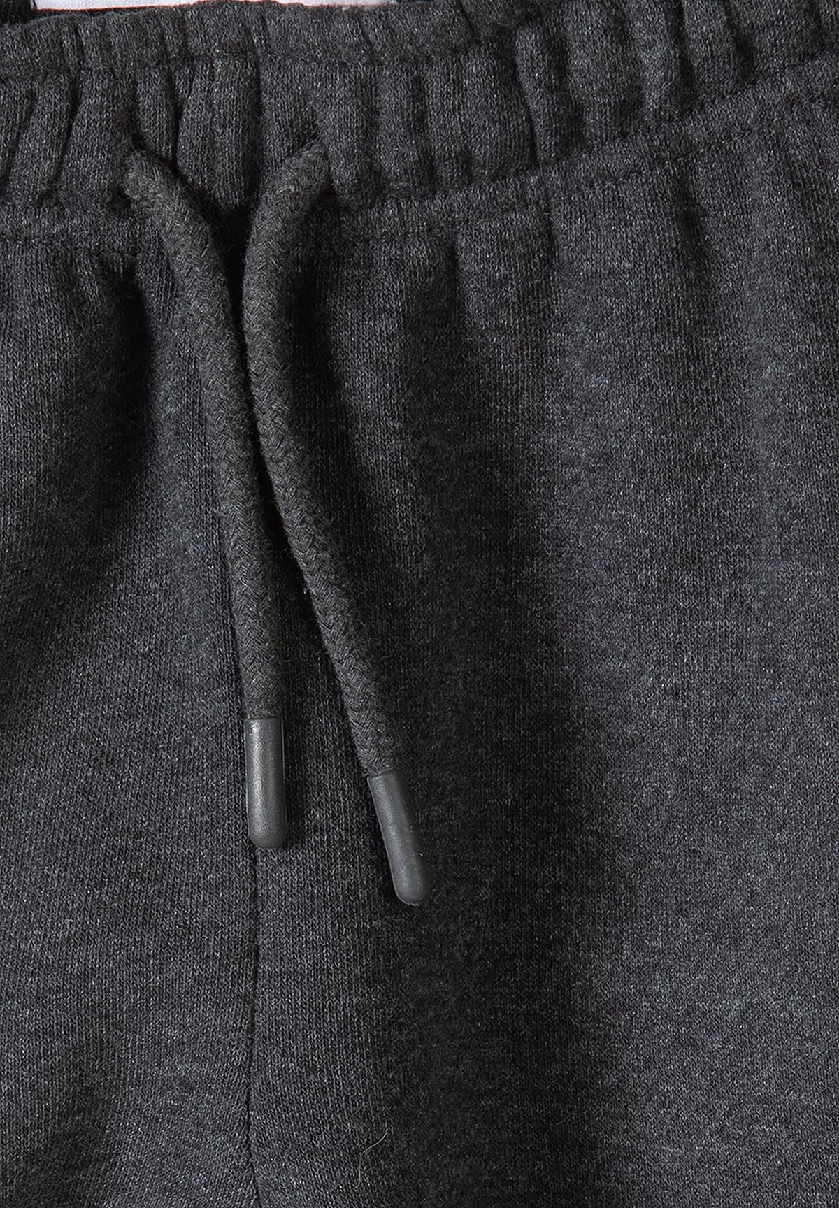 Close-up of charcoal joggers' elastic waistband and dark drawcord.
