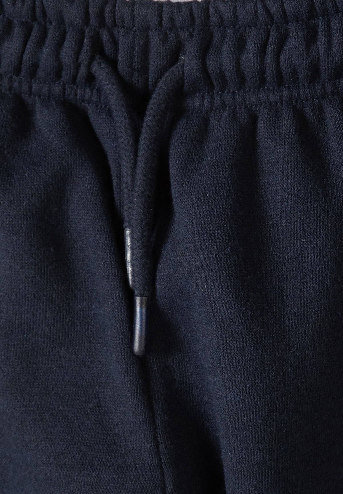 Close-up of navy joggers' elastic waist and matching braided drawcord.