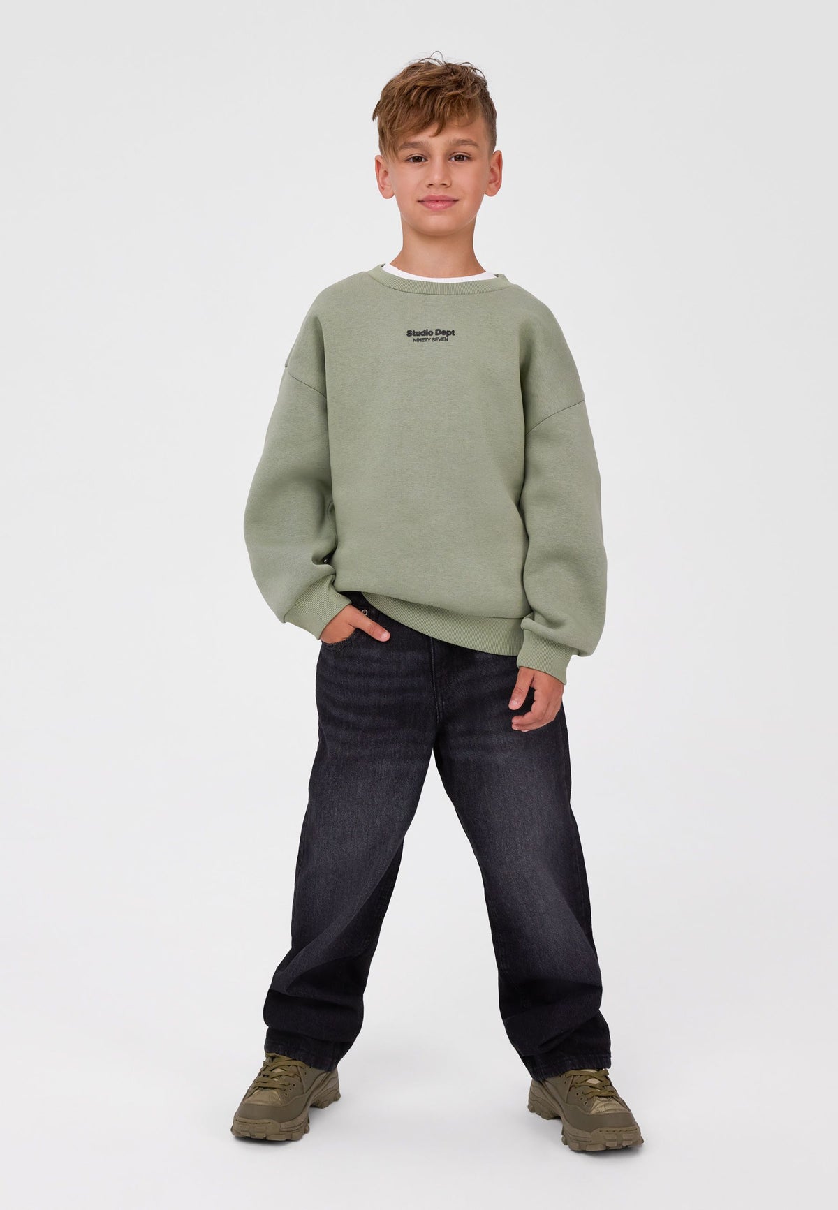 Boy wearing washed black baggy jeans with loose straight legs and front hip pockets.