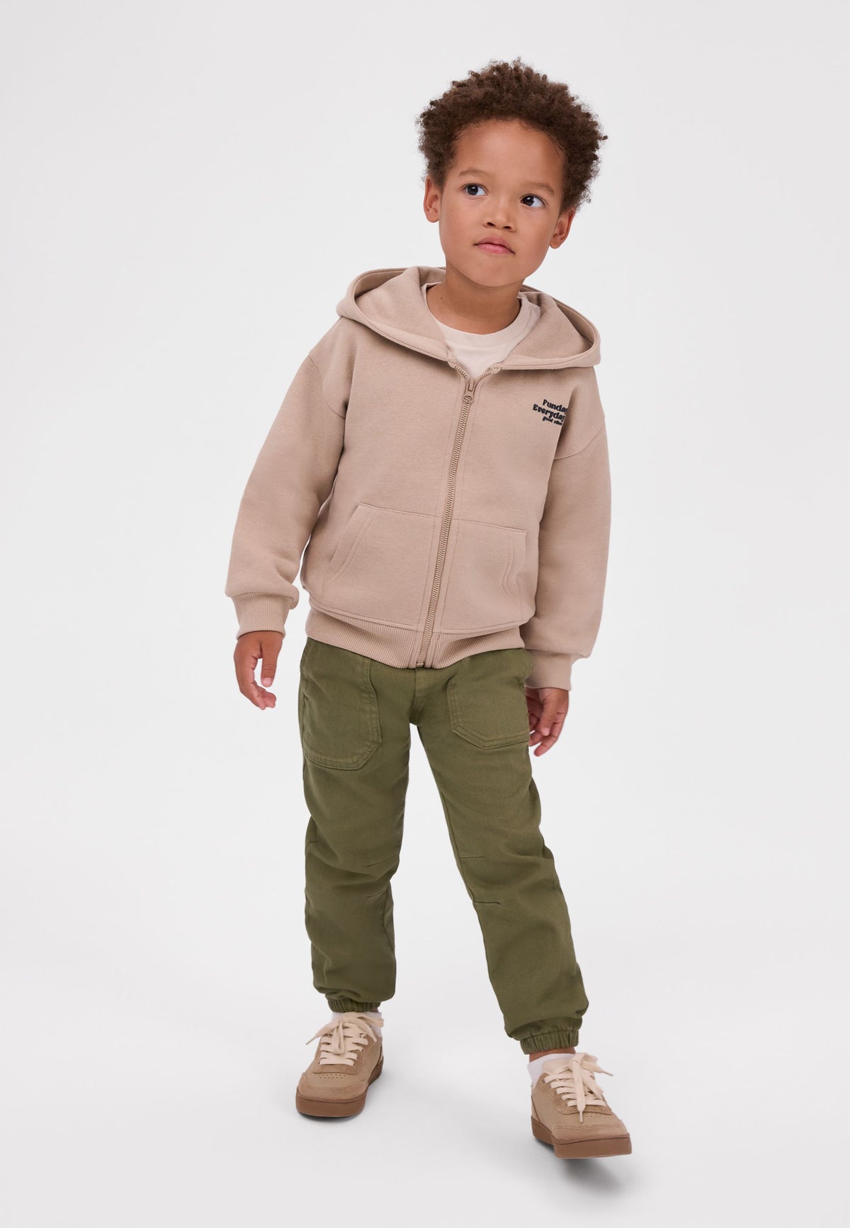 Boy wearing olive green trousers with front patch pockets and gathered ankles.