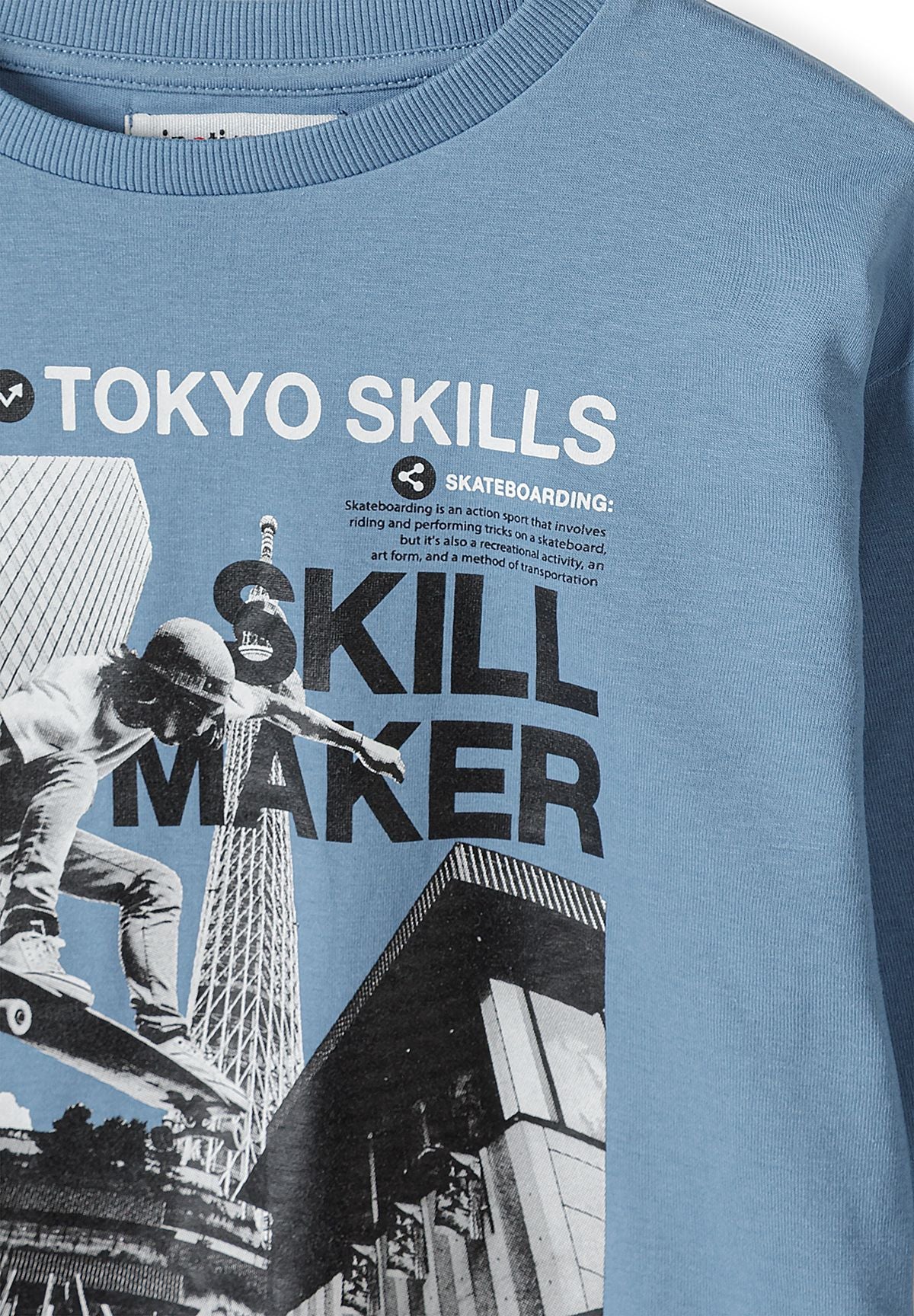 Close-up of skateboarder, Tokyo city image and SKILL MAKER print on a blue top.