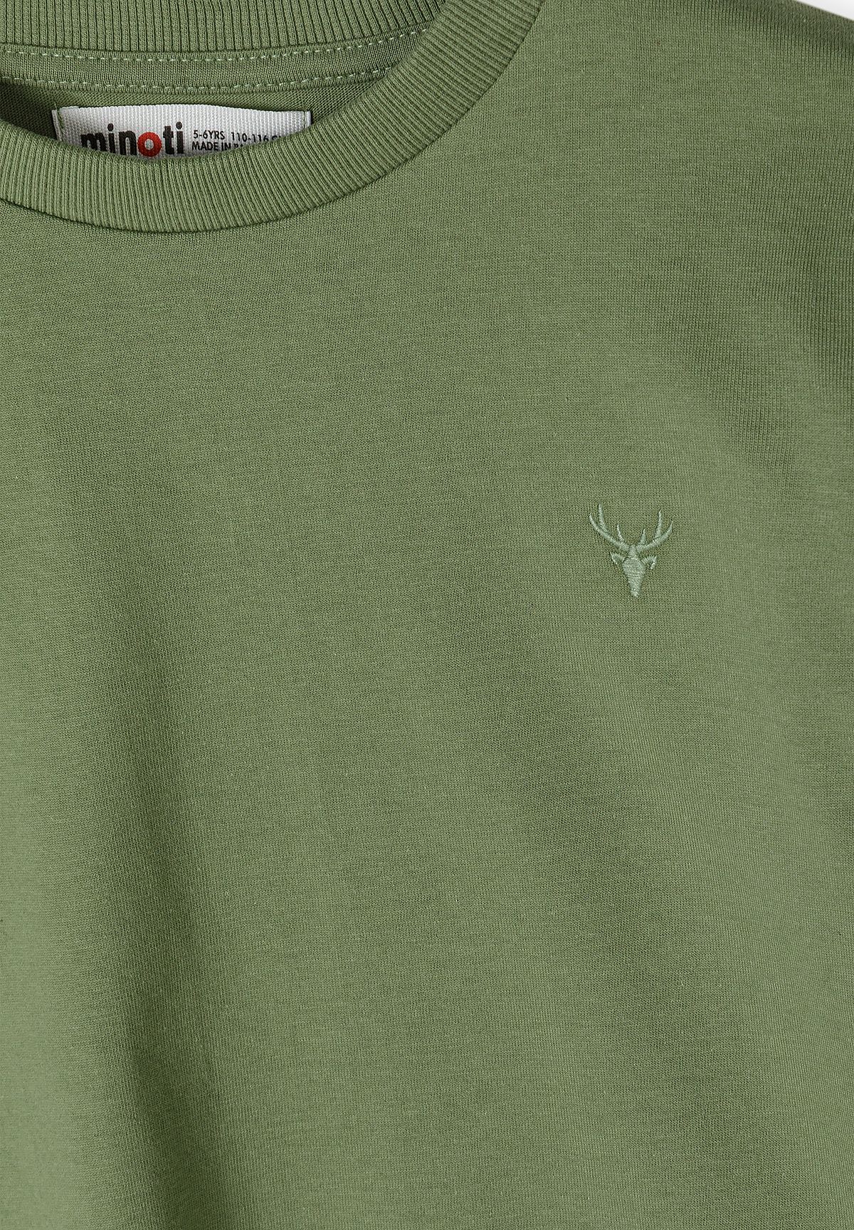 Close-up of small stag-head embroidery on olive green top.