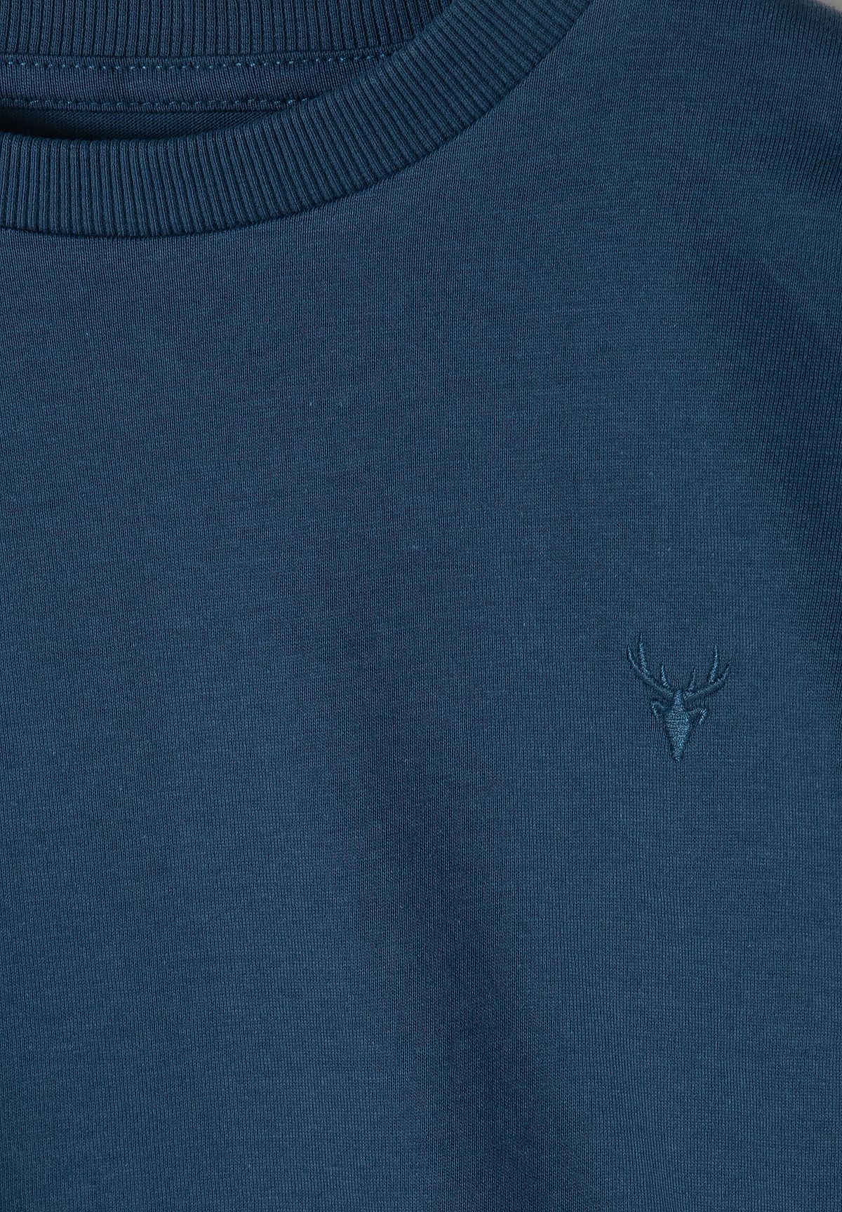 Close-up of tonal stag-head embroidery on navy top with ribbed neckline.