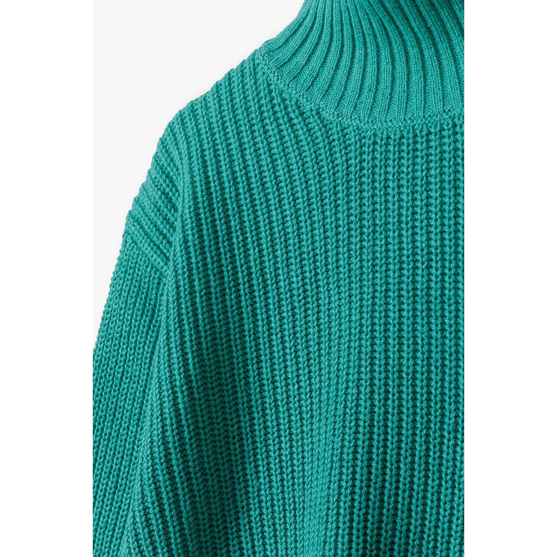 Close-up detail of deep green turtleneck collar and shoulder showing chunky ribbed knit texture and rolled neckline