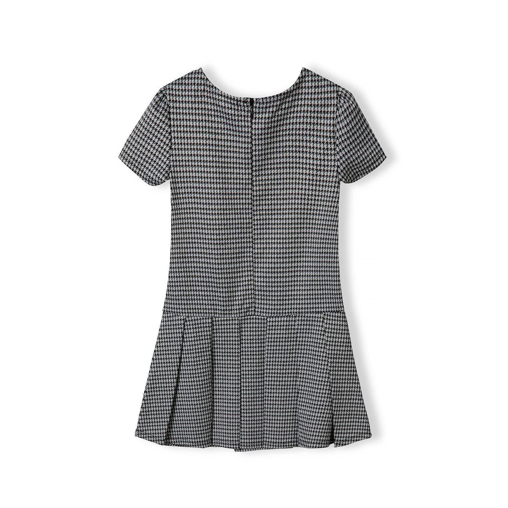 Black and white dogtooth dress laid flat showing short sleeves and pleated skirt design, back view on white background
