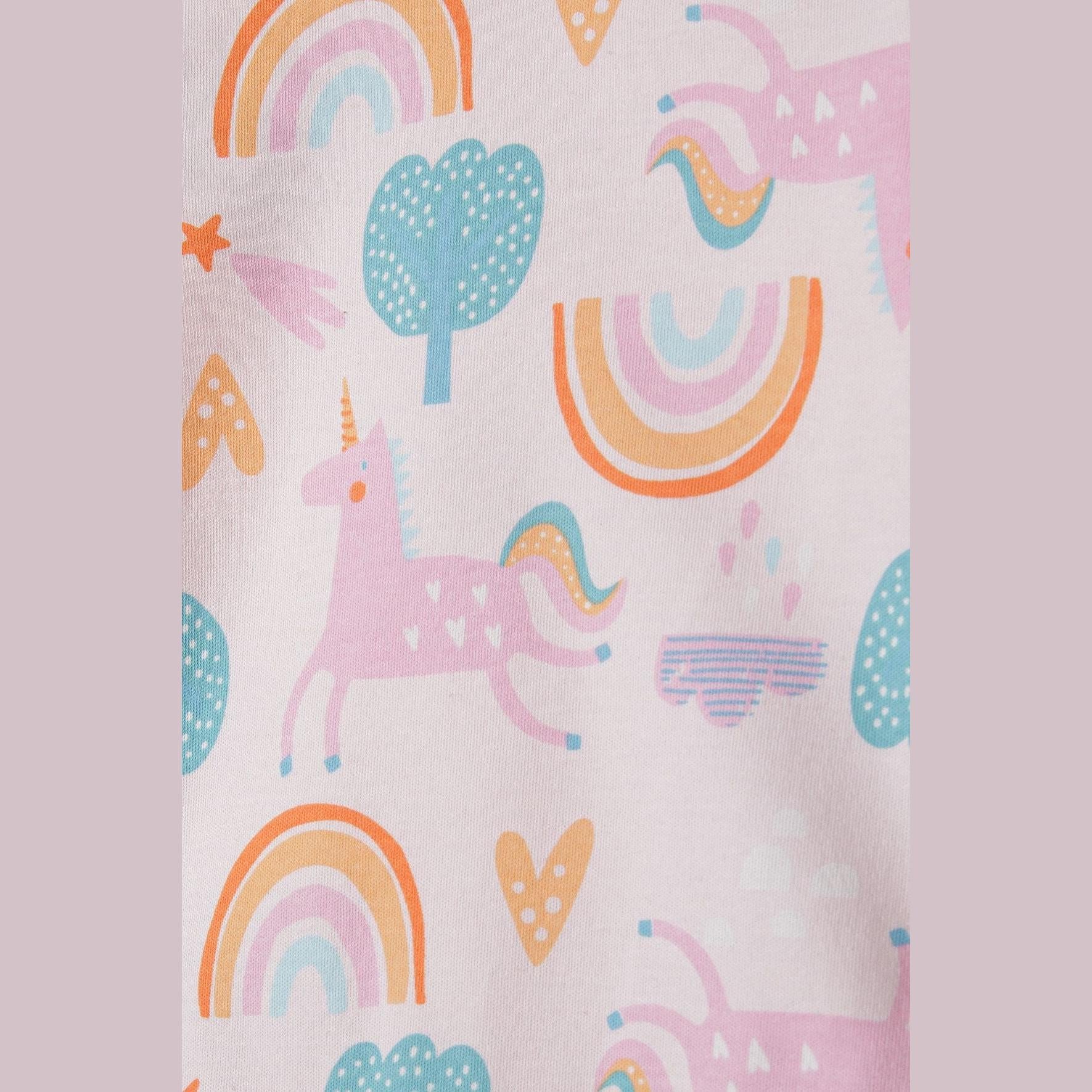 Close-up detail of the whimsical print showing colorful rainbows, pink unicorns, dotted trees and orange hearts on light pink fabric