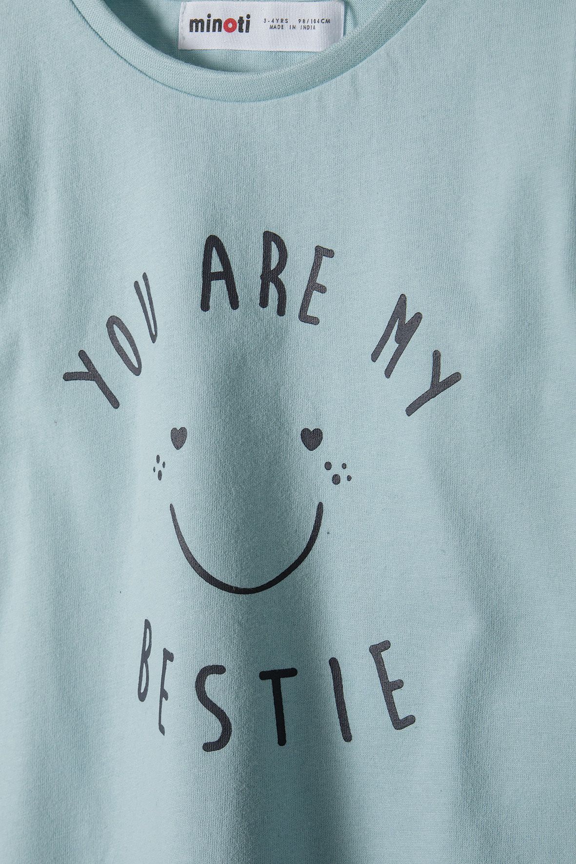 Close-up of mint T-shirt's black 'YOU ARE MY BESTIE' lettering and heart-eyed smiley.