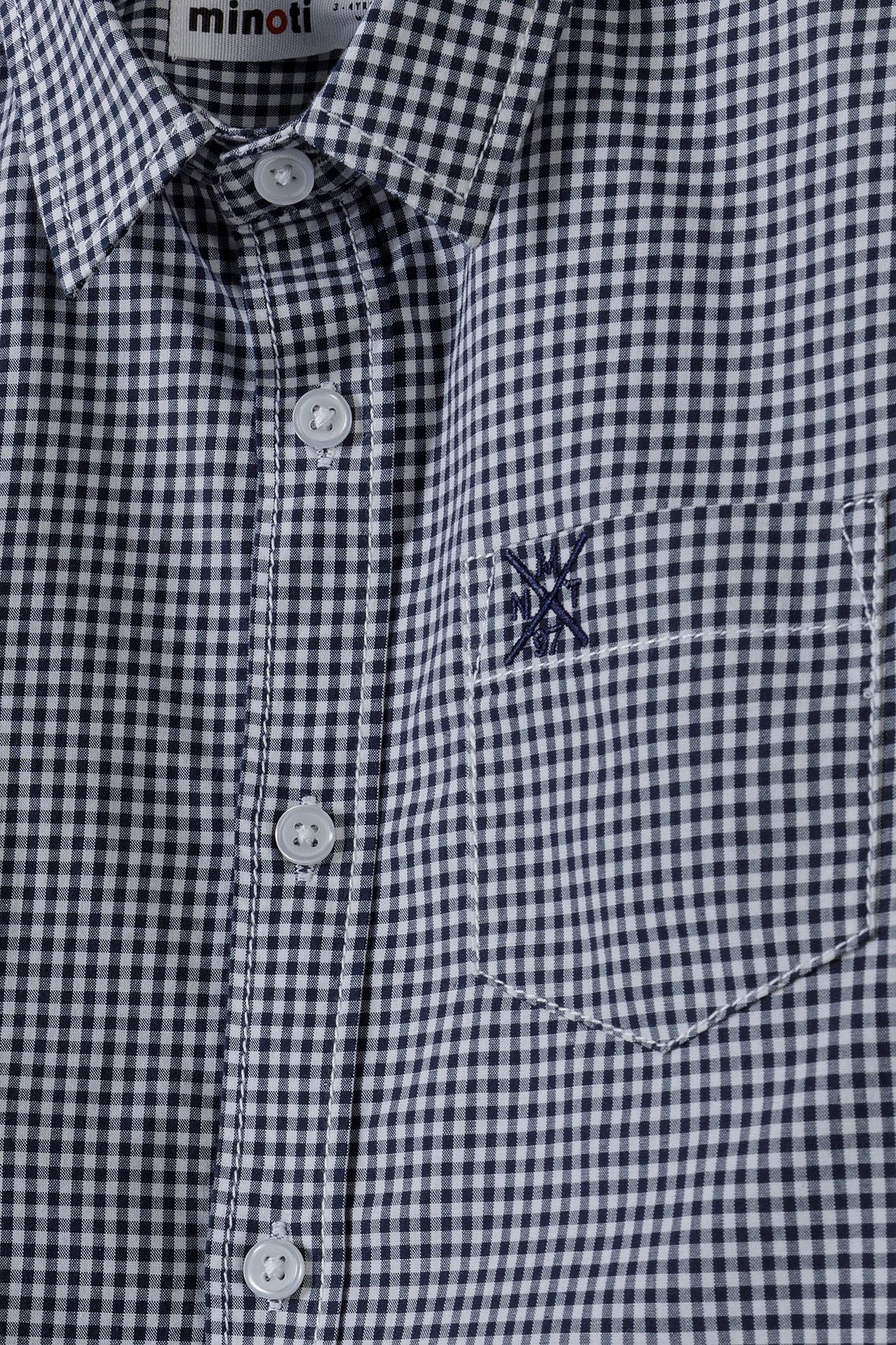 Close-up of navy-white gingham shirt's pointed collar, white buttons and embroidered pocket.