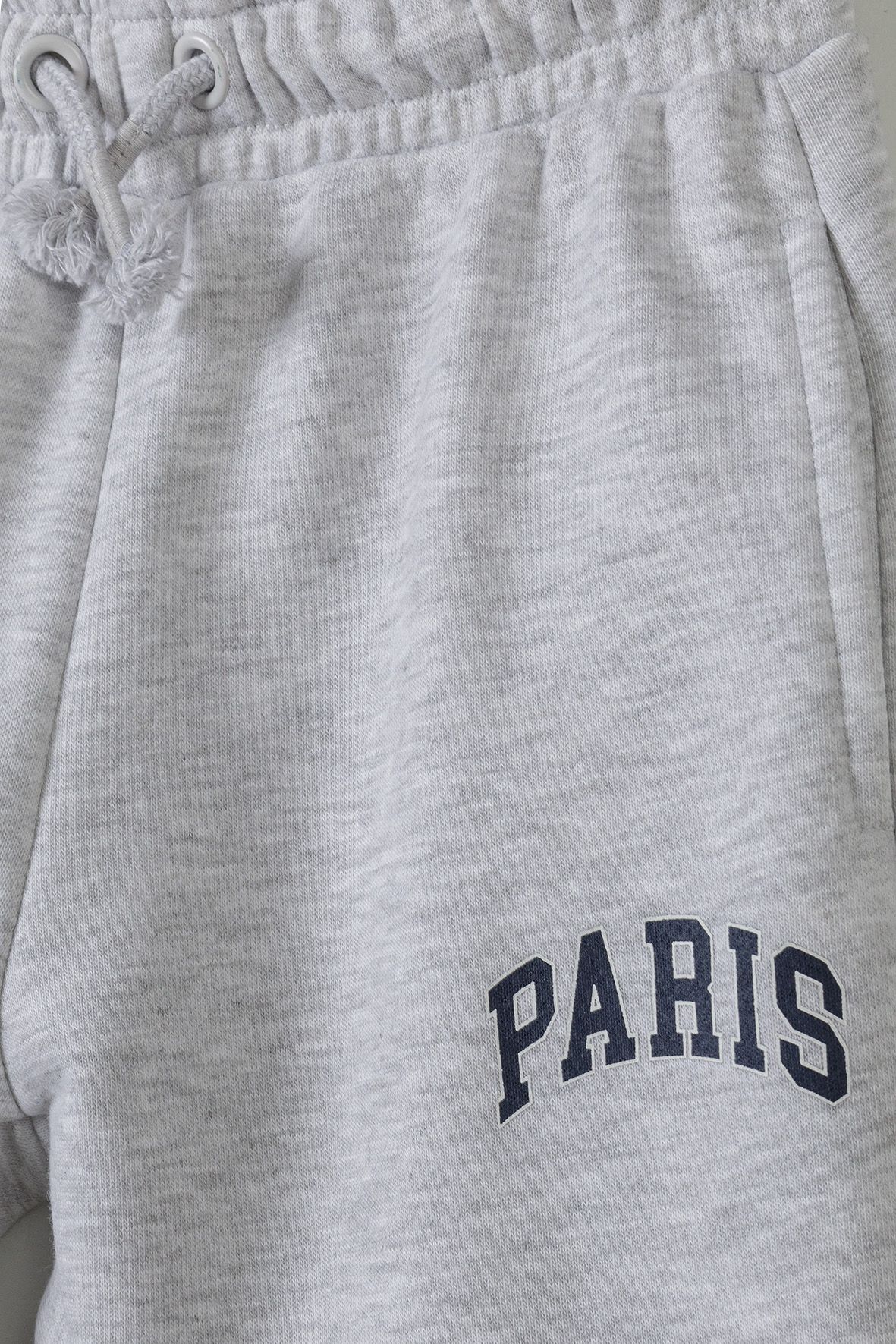 Close-up of grey jogger drawcord, pocket and arched PARIS print.