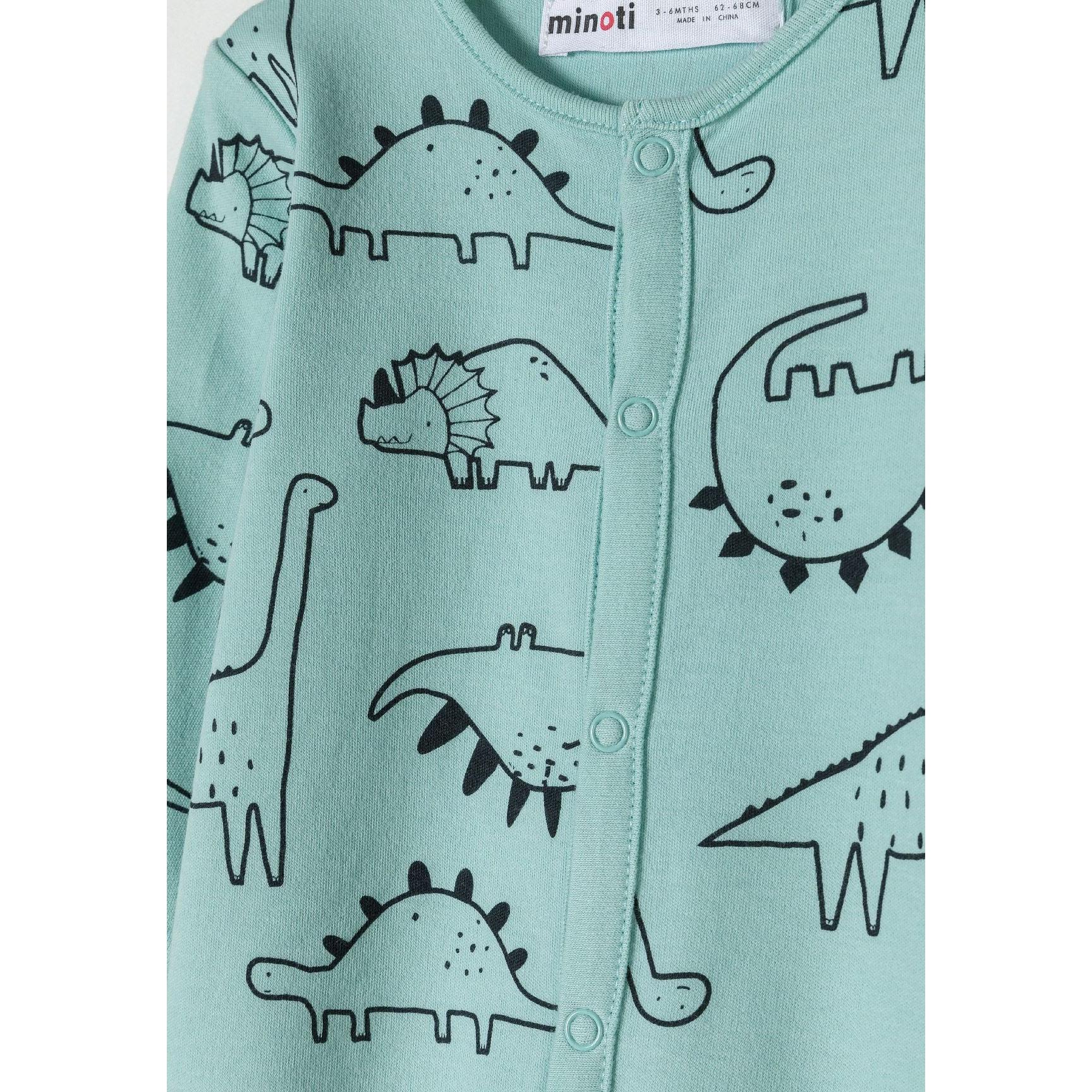 Close-up detail of mint green sleepsuit showing black outlined dinosaur prints and snap button fastenings with Minoti label