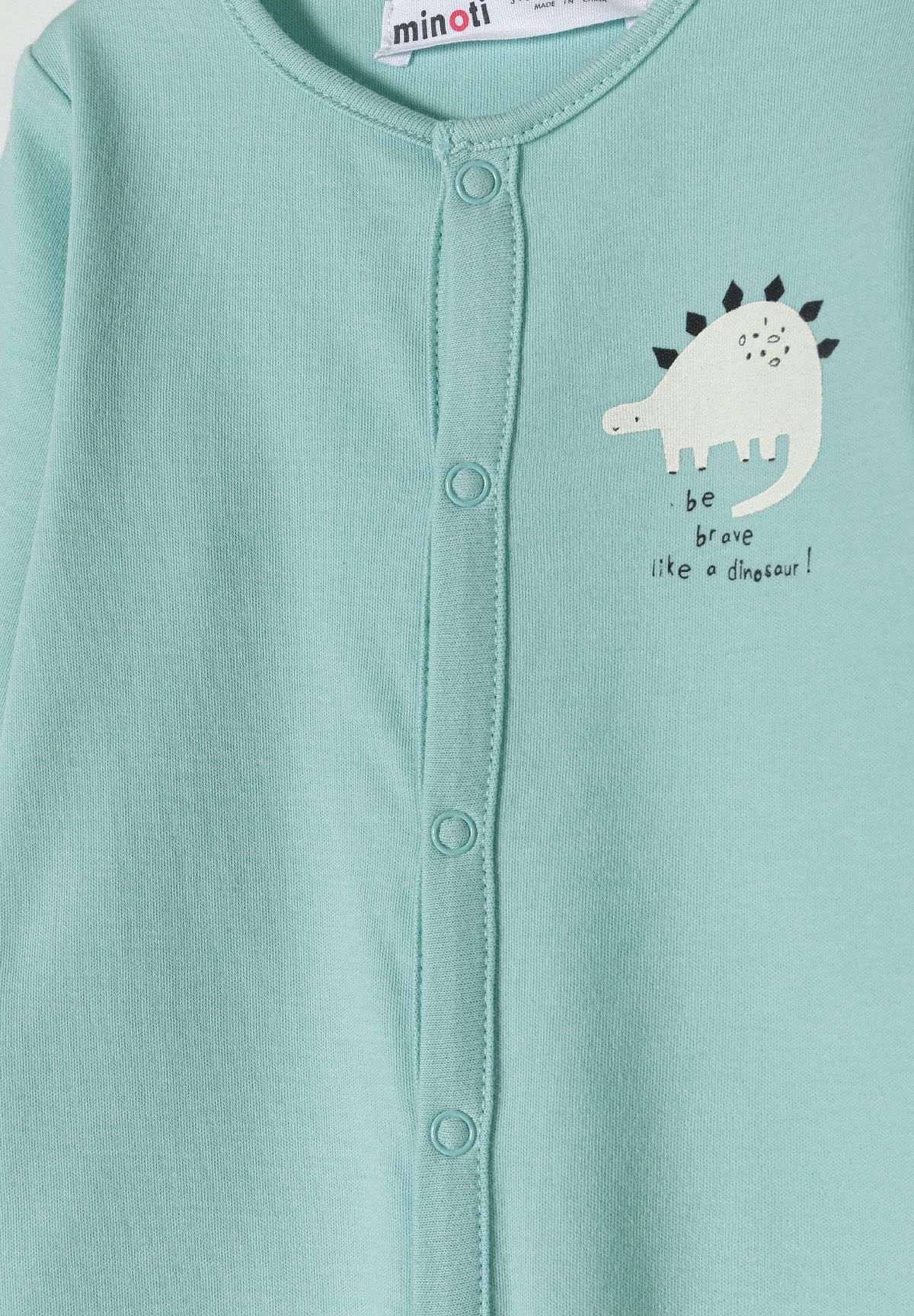 Close-up of mint sleepsuit's snap fastening and white dinosaur chest print.