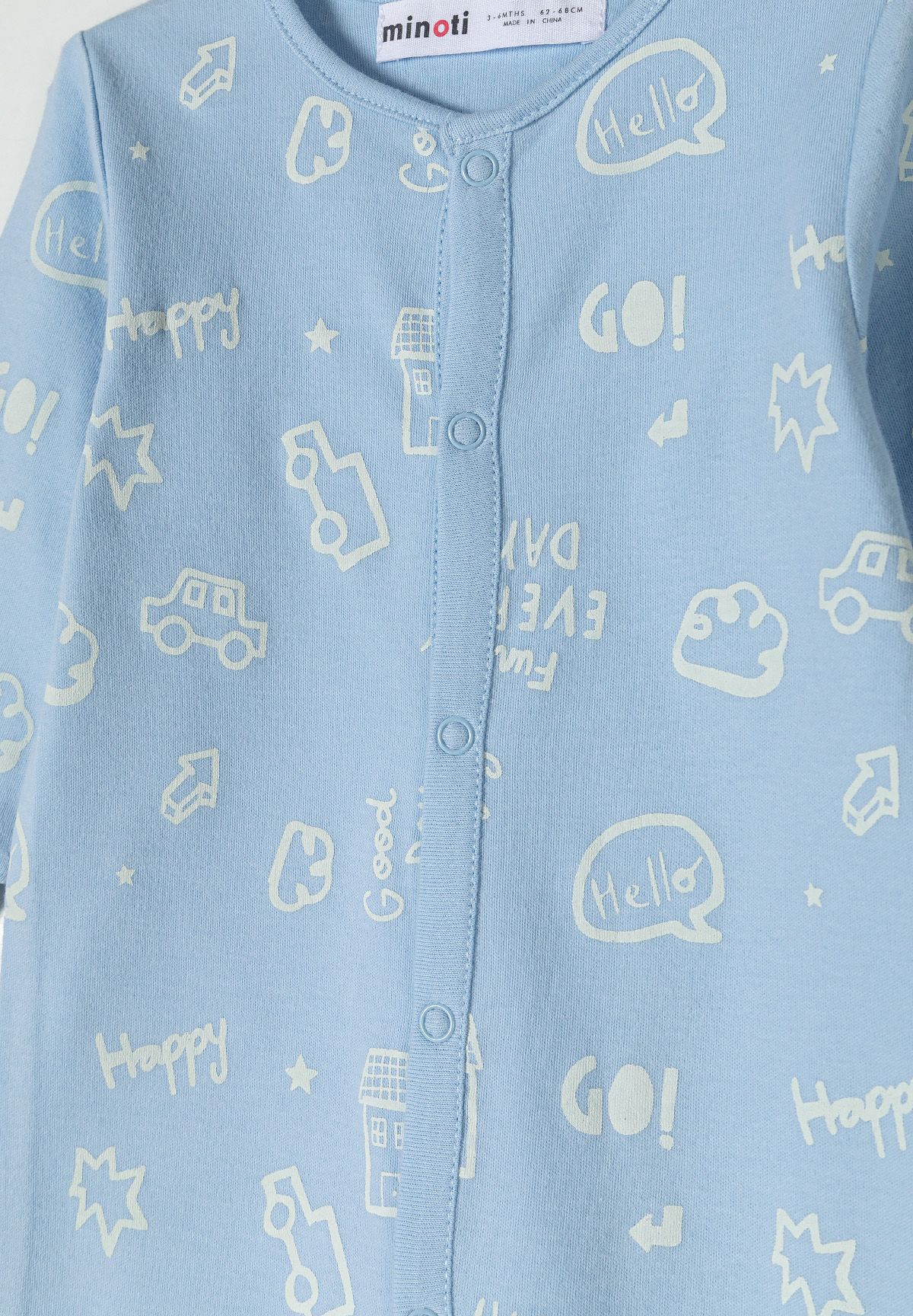 Detail of a boys' sleepsuit in light blue with printed patterns and press studs.