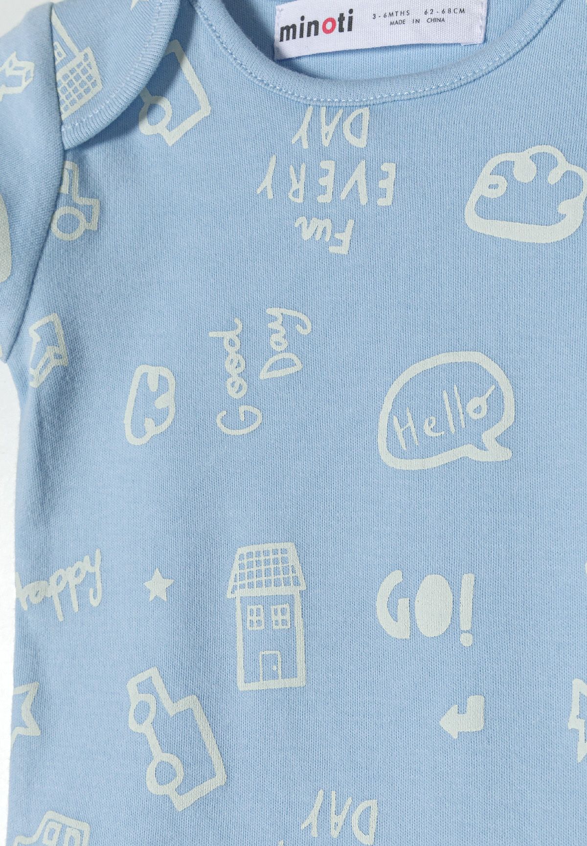 Close-up of light-blue bodysuit with white cars, speech bubbles, houses and text doodles.