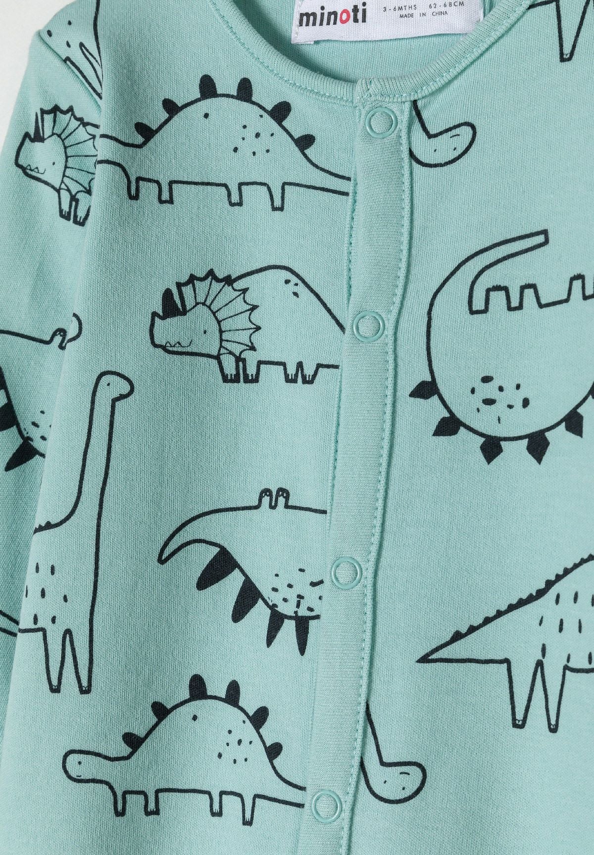 Detail of a mint long sleeve sleepsuit for boys with dinosaur print and press stud fastening.
