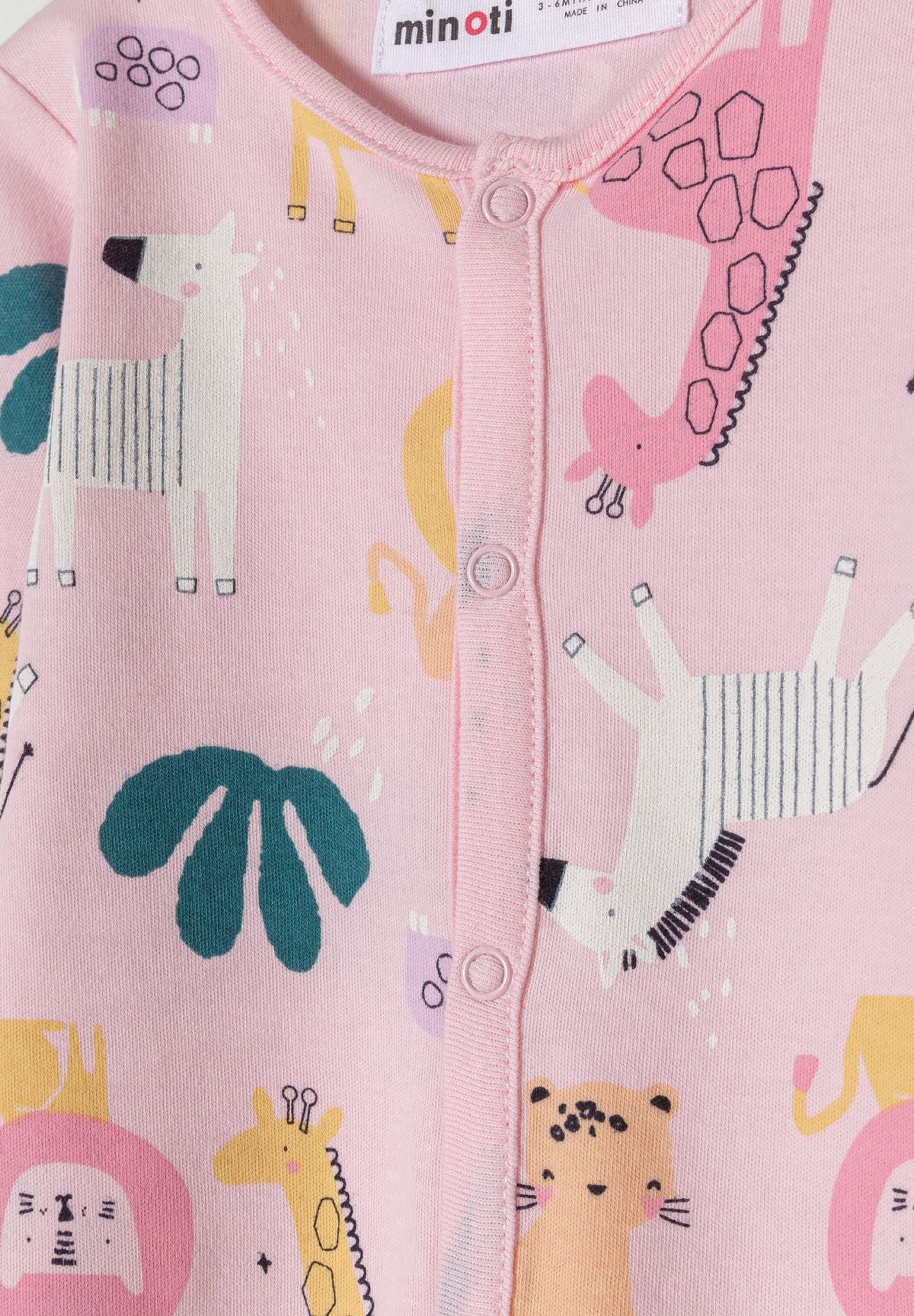 Detail of a girls' long-sleeve sleepsuit in pink with animal prints and front press-stud fastening.