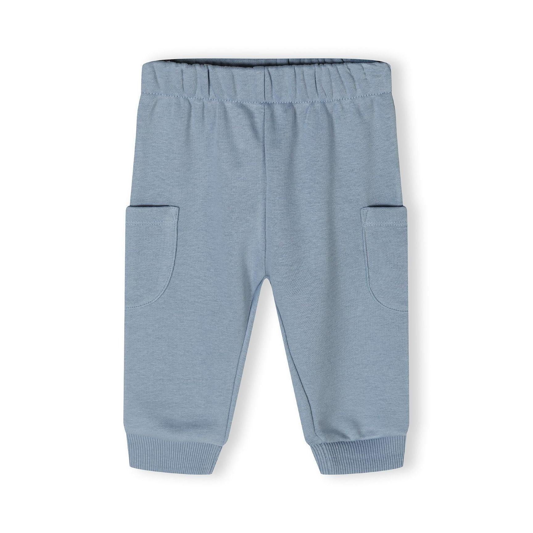 Close-up view of blue joggers showing elasticated waistband and side pockets detail on white background